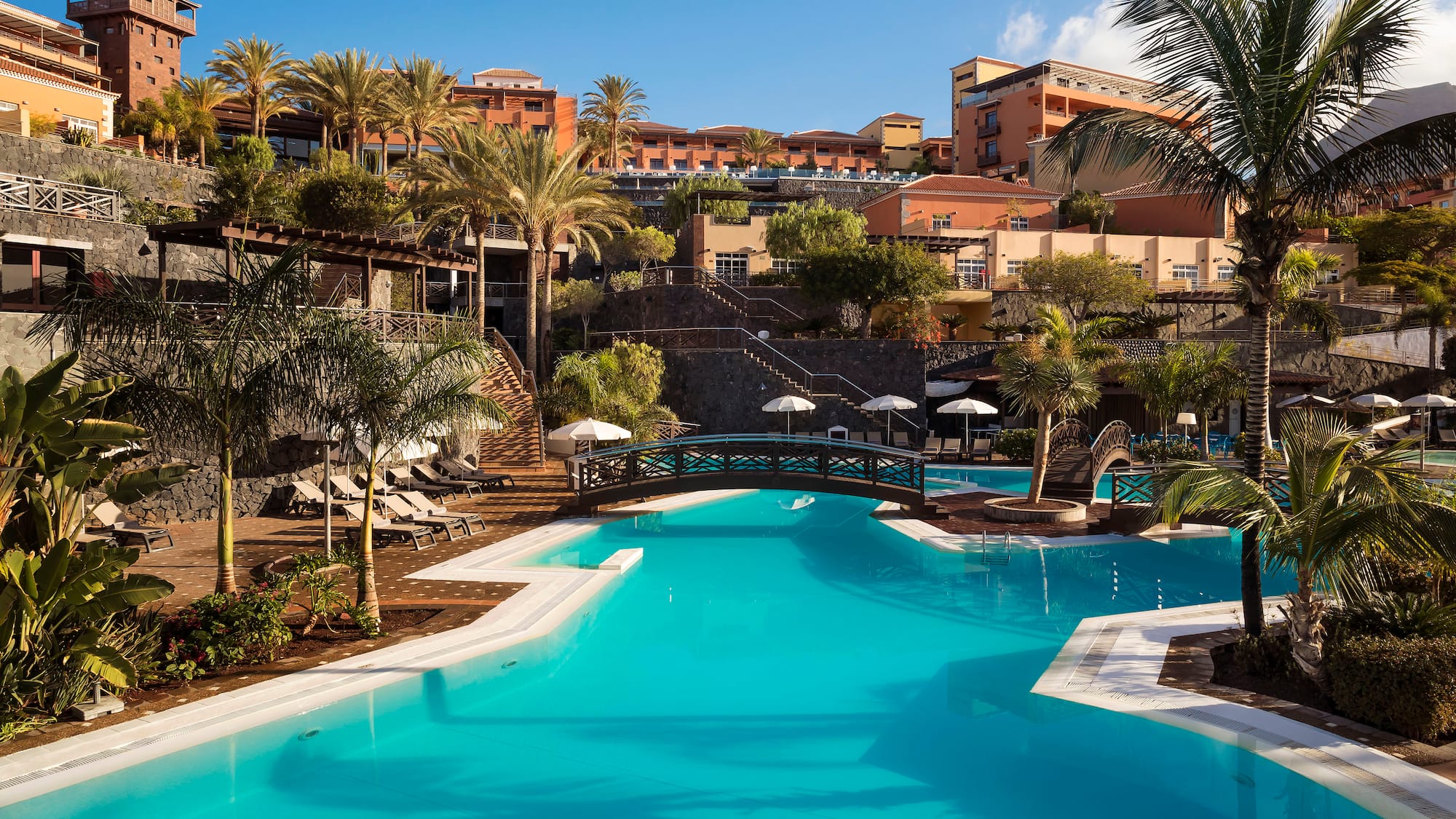 a swimming pool with palm trees and buildings in the background