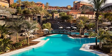 a swimming pool with palm trees and buildings in the background