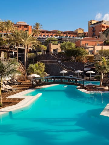 a swimming pool with palm trees and buildings in the background