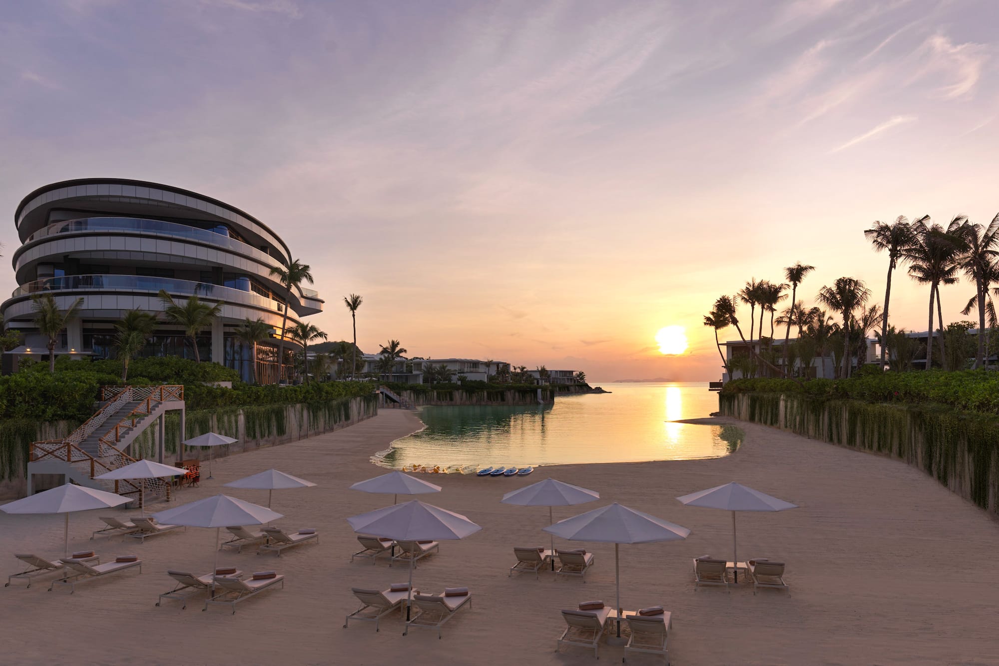 Luxury beach resort sunset: modern hotel, sandy beach, umbrellas, calm ocean.