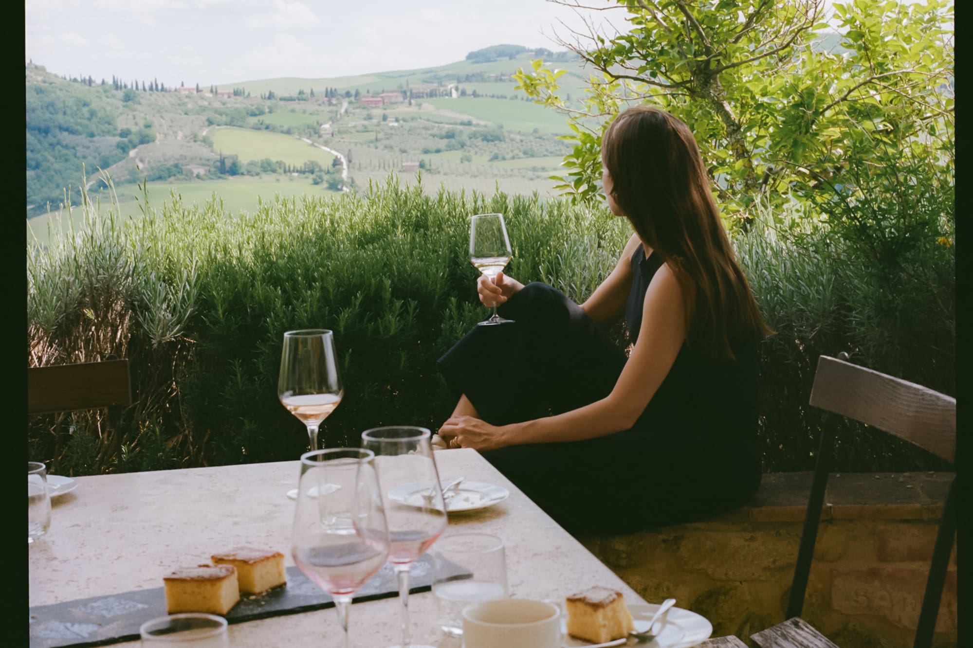 a woman sitting at a table with wine glasses