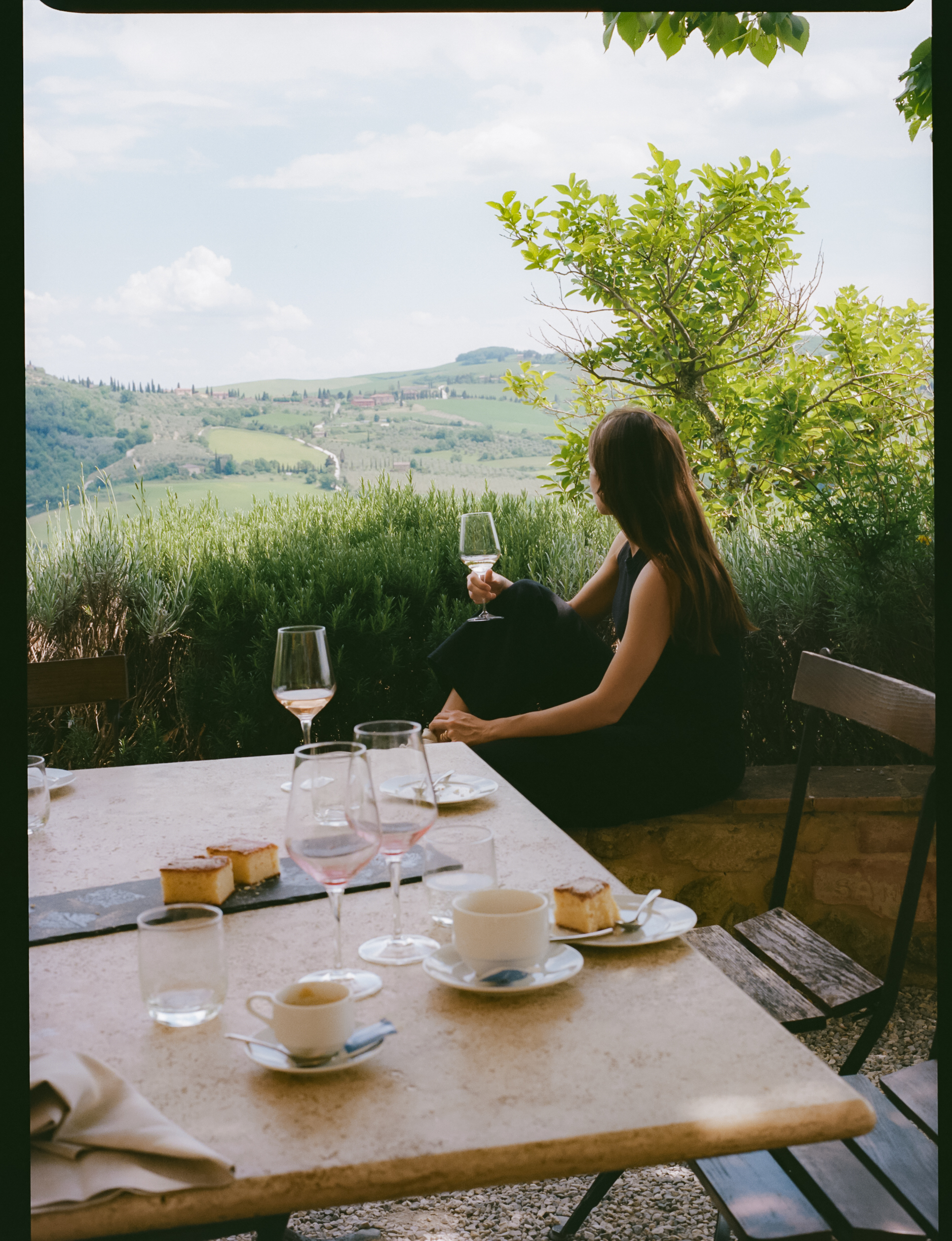 a woman sitting at a table with wine glasses