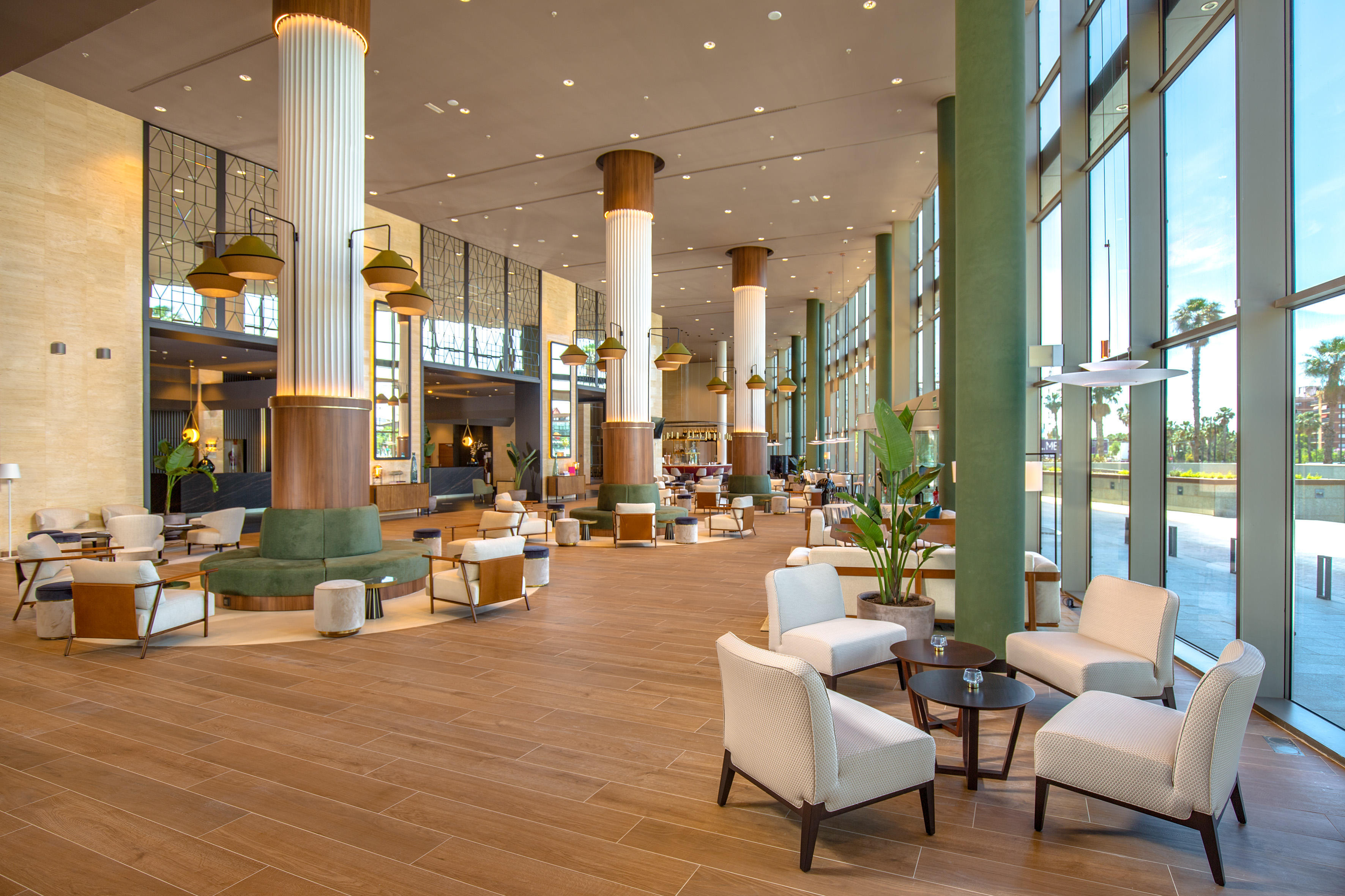 Modern hotel lobby with spacious seating areas, tall columns, and large windows.