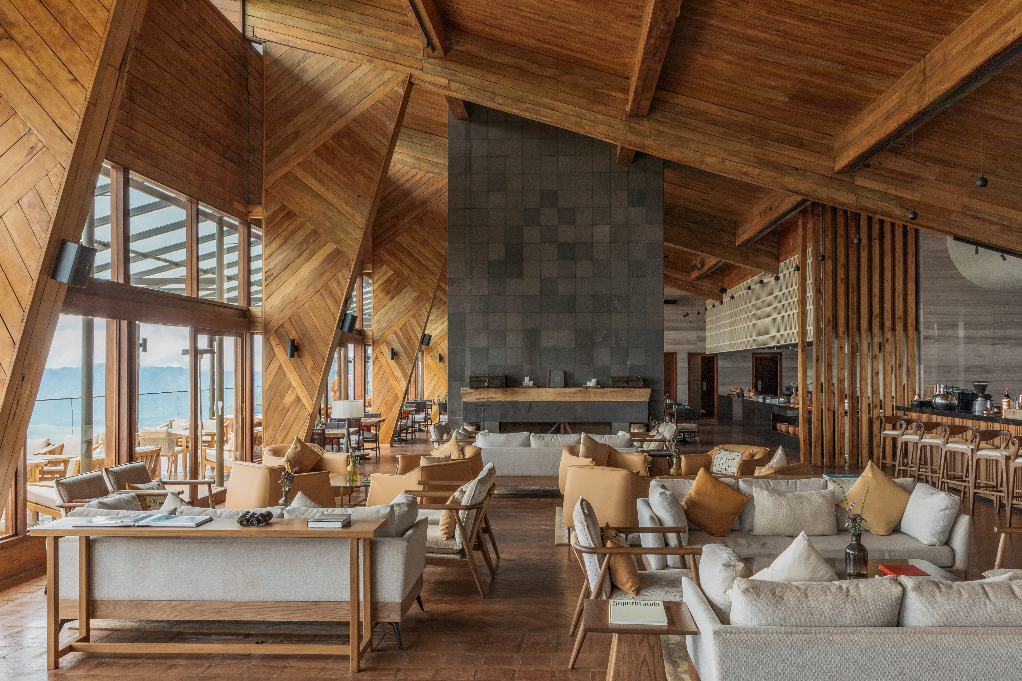 Cozy lodge lounge with wood paneling, stone fireplace, and mountain view.