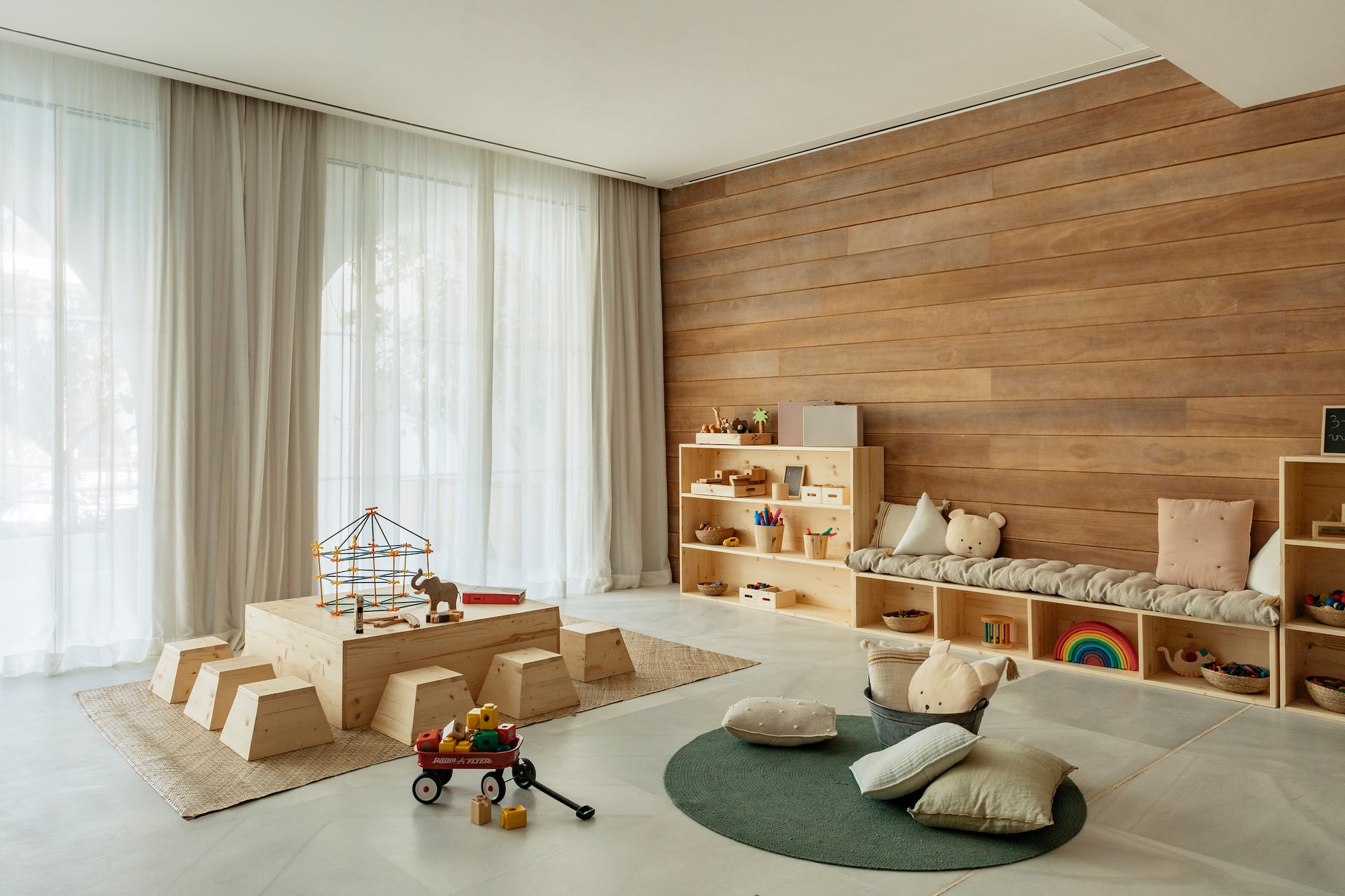Bright children's playroom with wooden furniture, toys, and natural decor.
