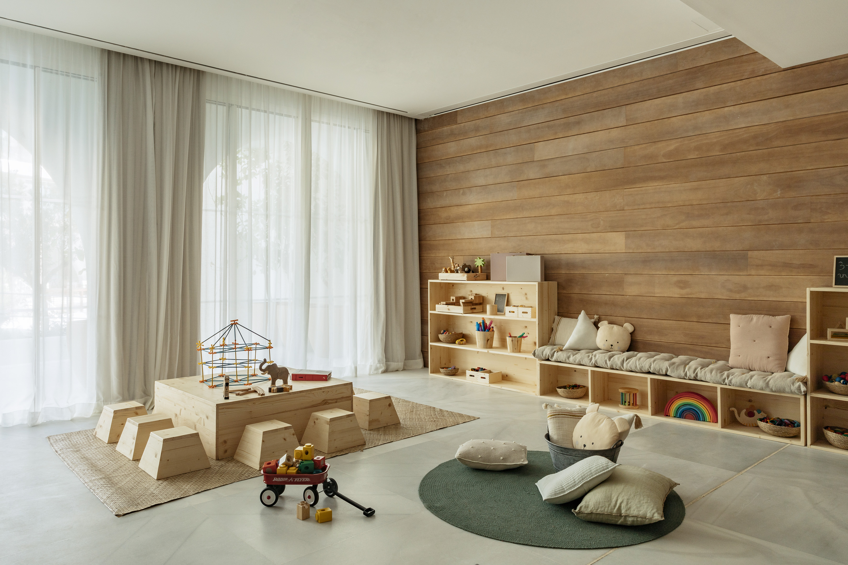 Bright children's playroom with wooden furniture, toys, and natural decor.