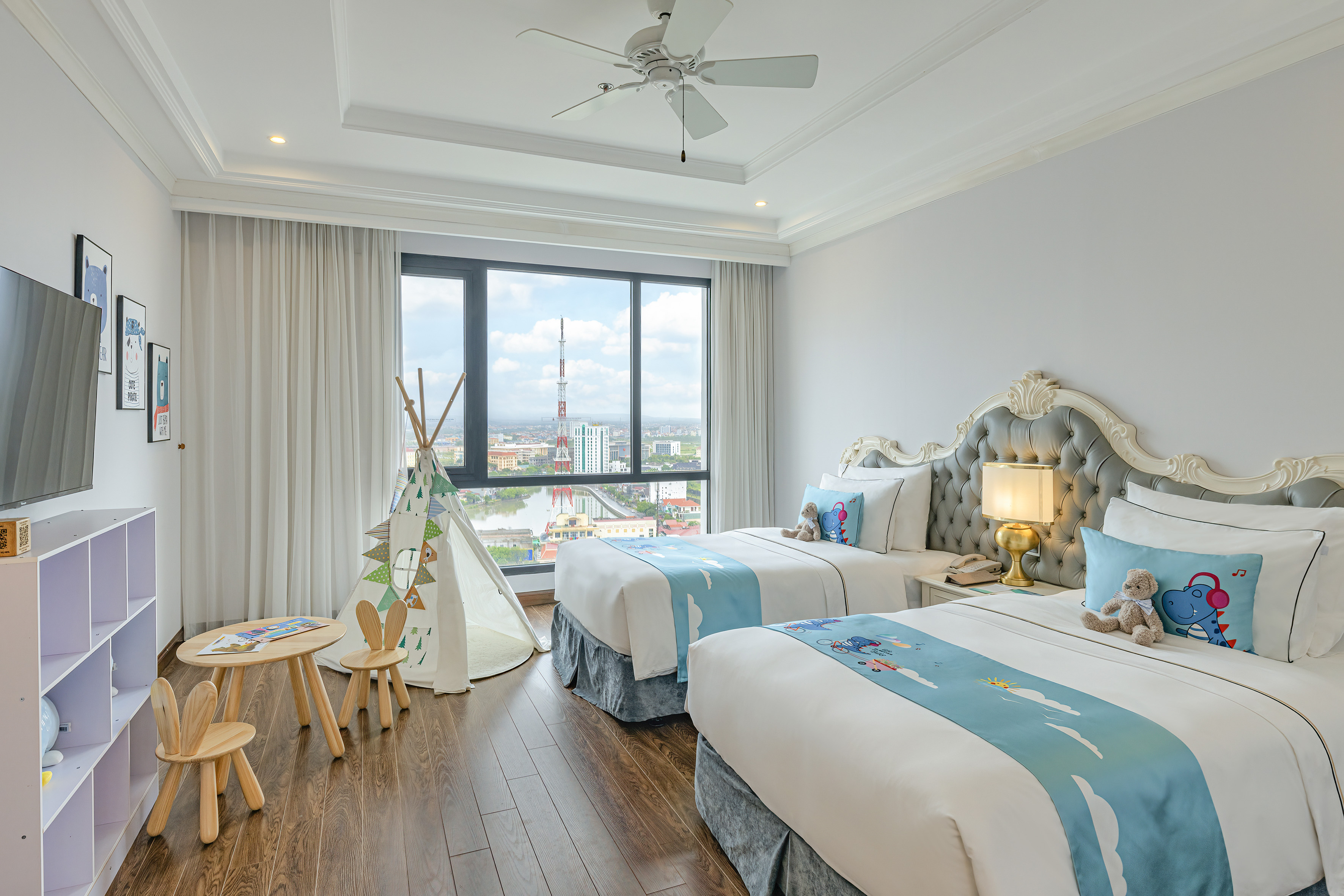 Family hotel room with twin beds, city view, and teepee play area.