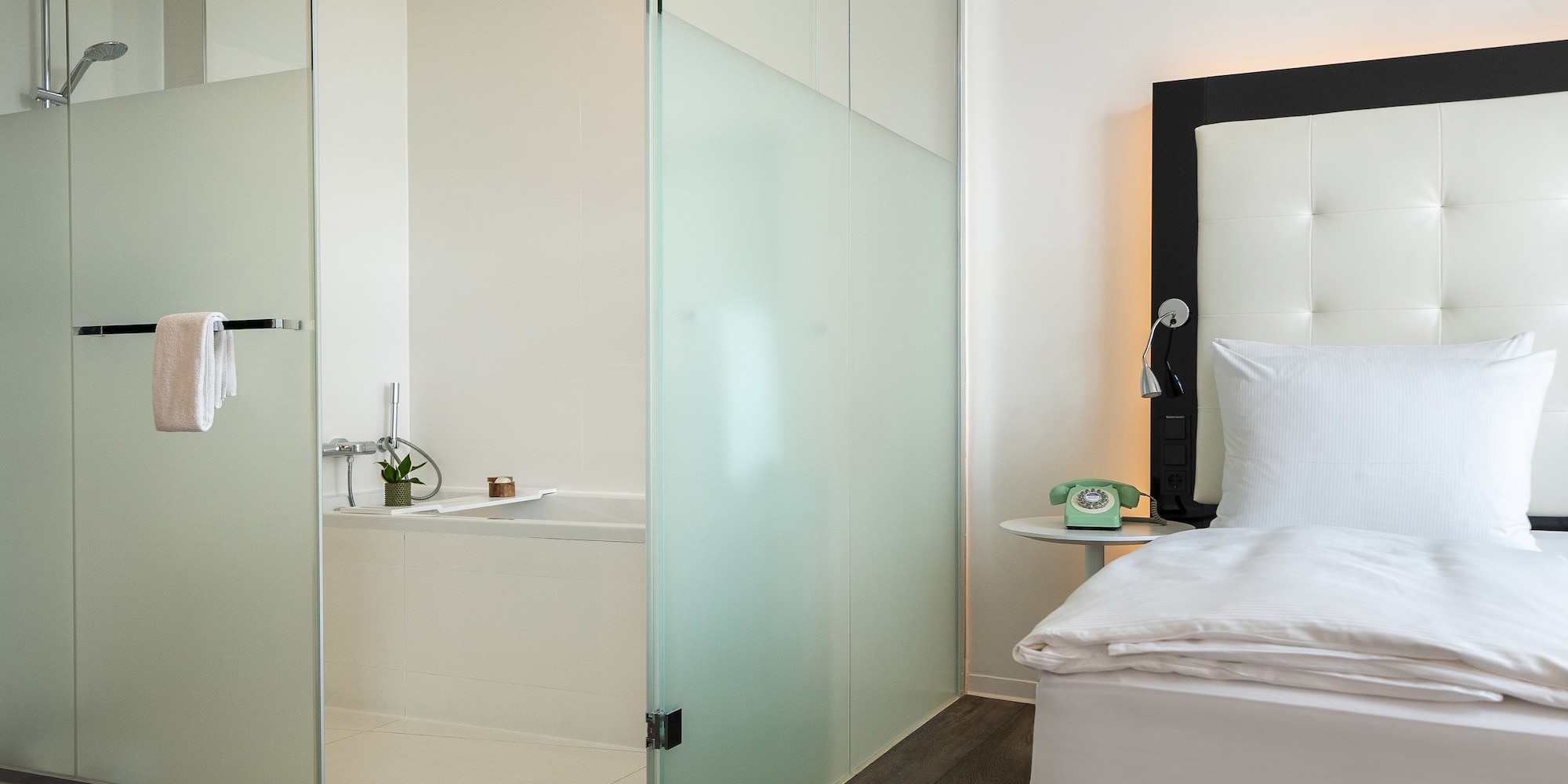 a room with a glass shower door and a bed