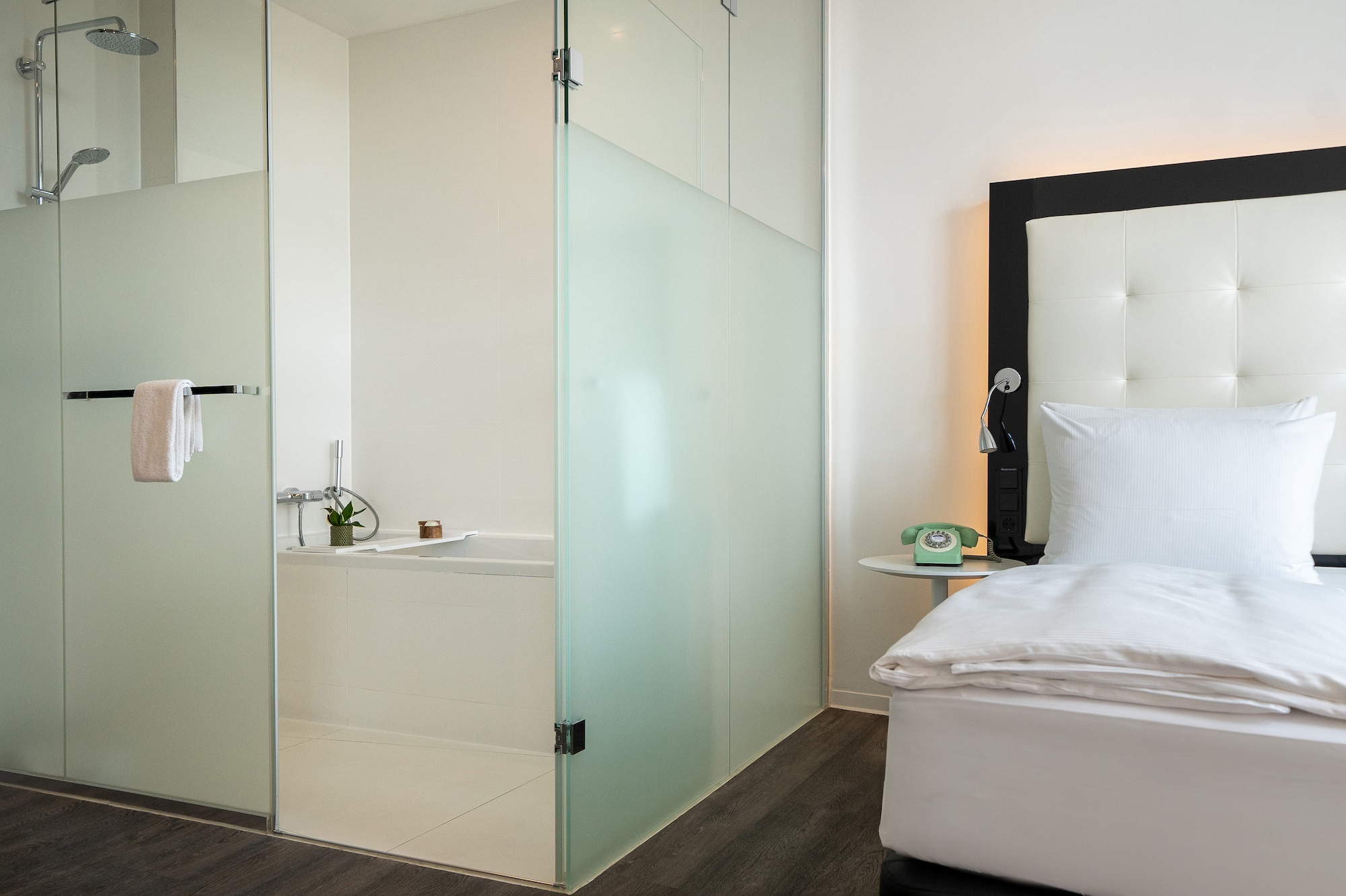 a room with a glass shower door and a bed