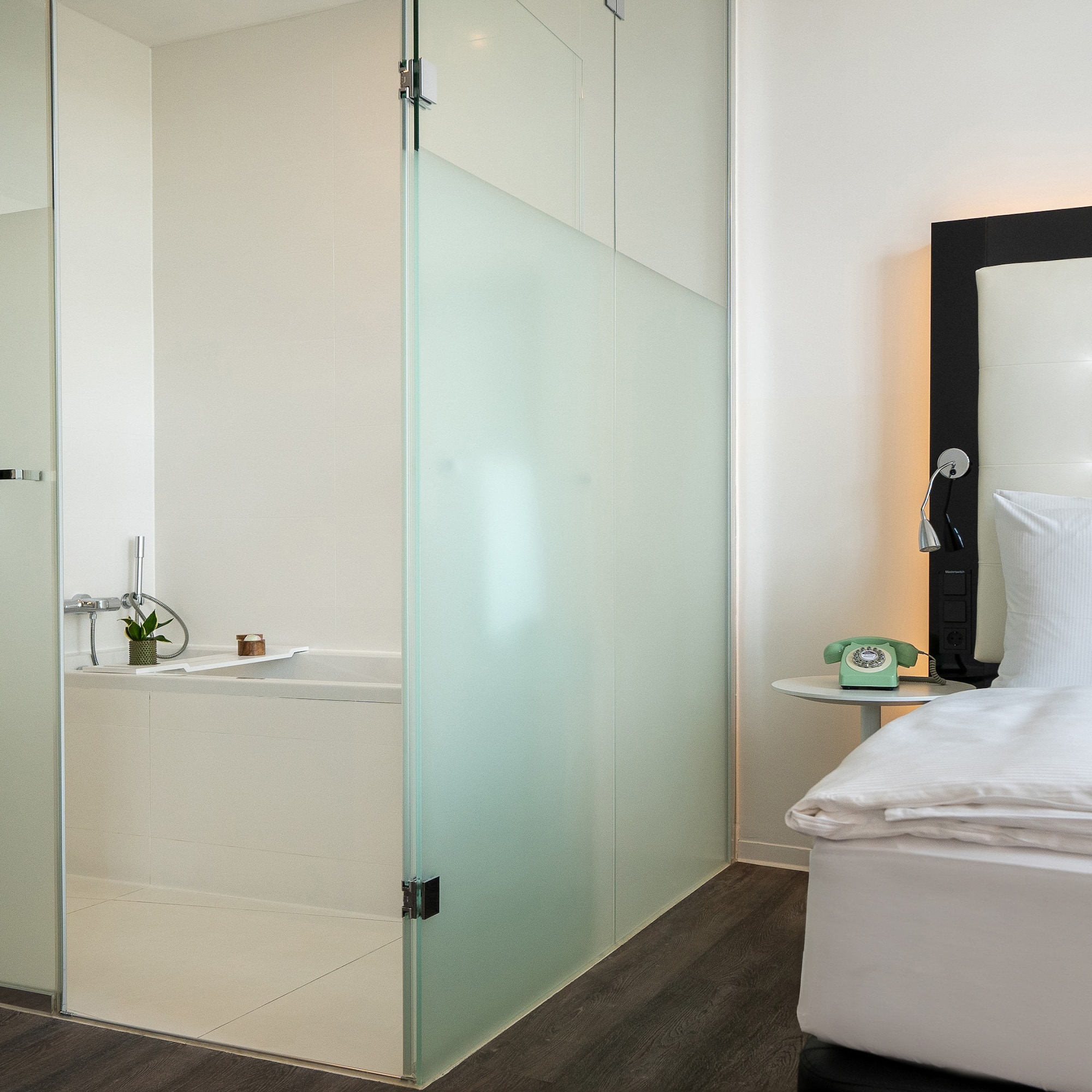 a room with a glass shower door and a bed