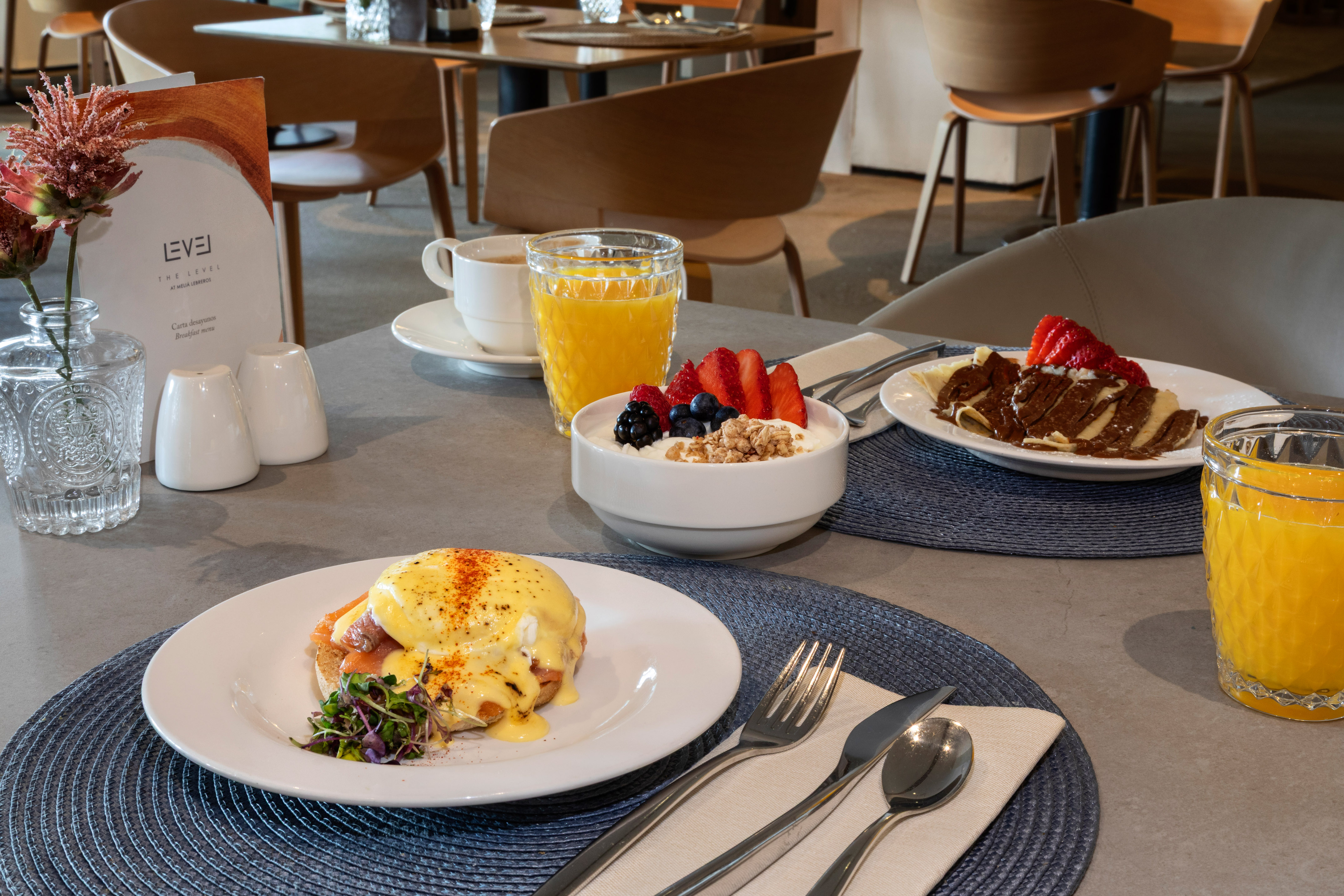 Breakfast spread: Eggs Benedict, berry yogurt, chocolate crepes, orange juice.