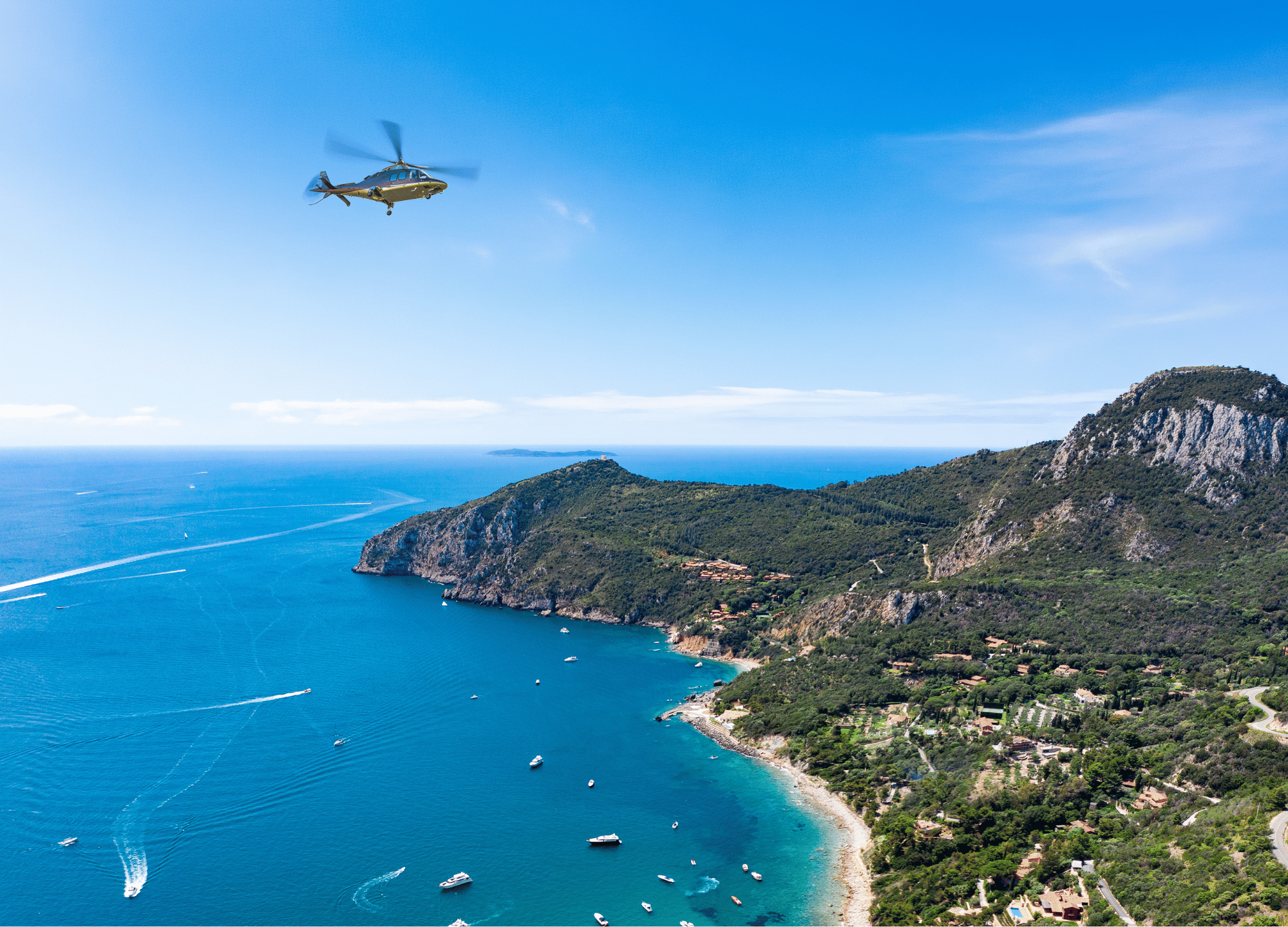 Helicopter aerial view of blue sea, green coastal mountains, and boats.