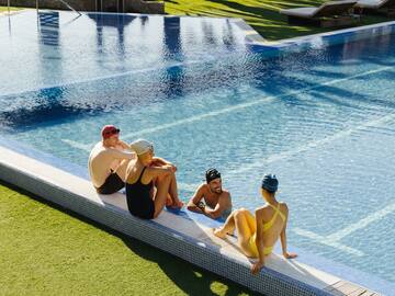a group of people sitting on a pool edge