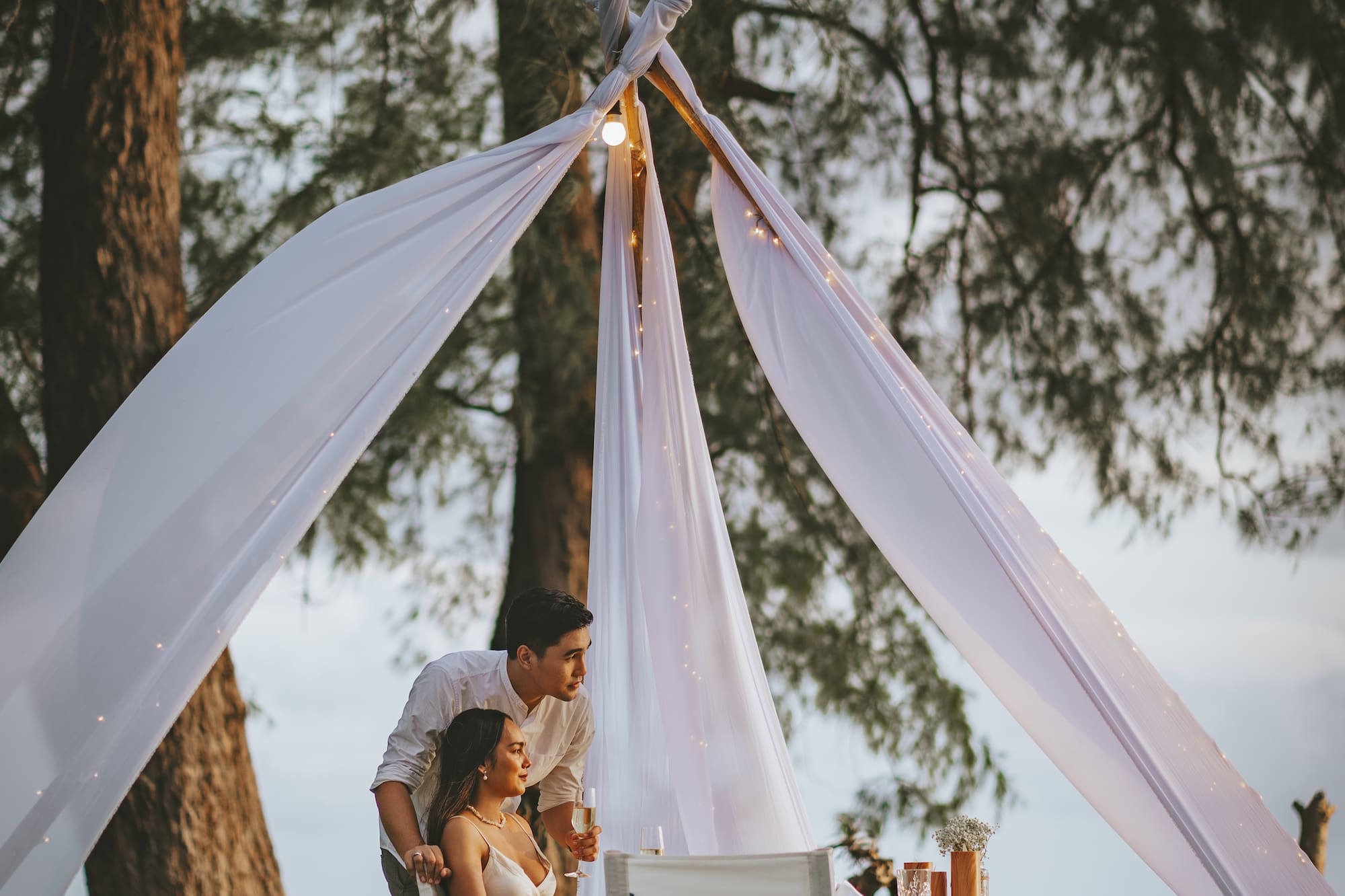 a man and woman sitting under a tent
