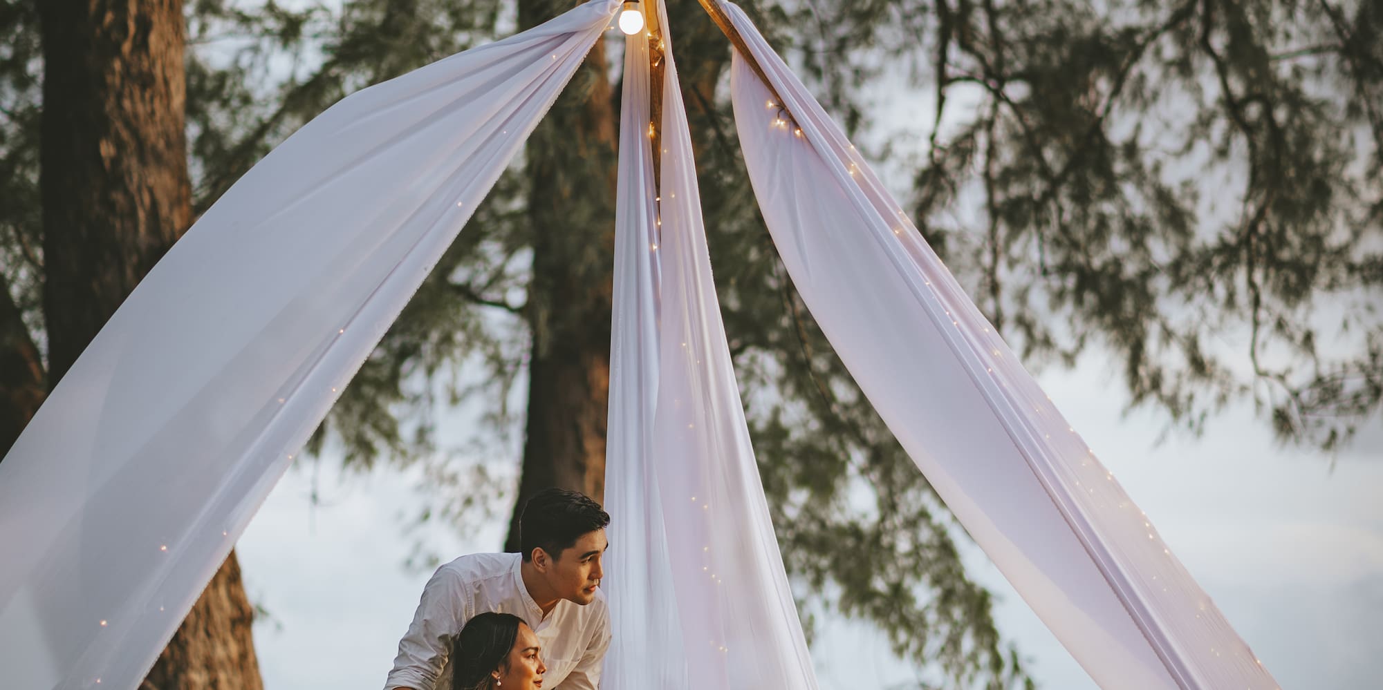 a man and woman sitting under a tent