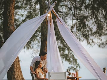 a man and woman sitting under a tent