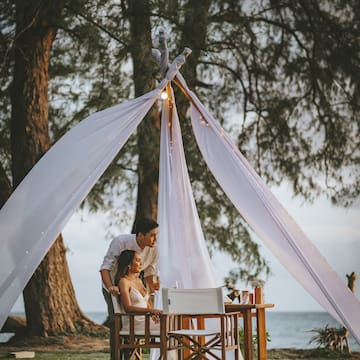a man and woman sitting under a tent