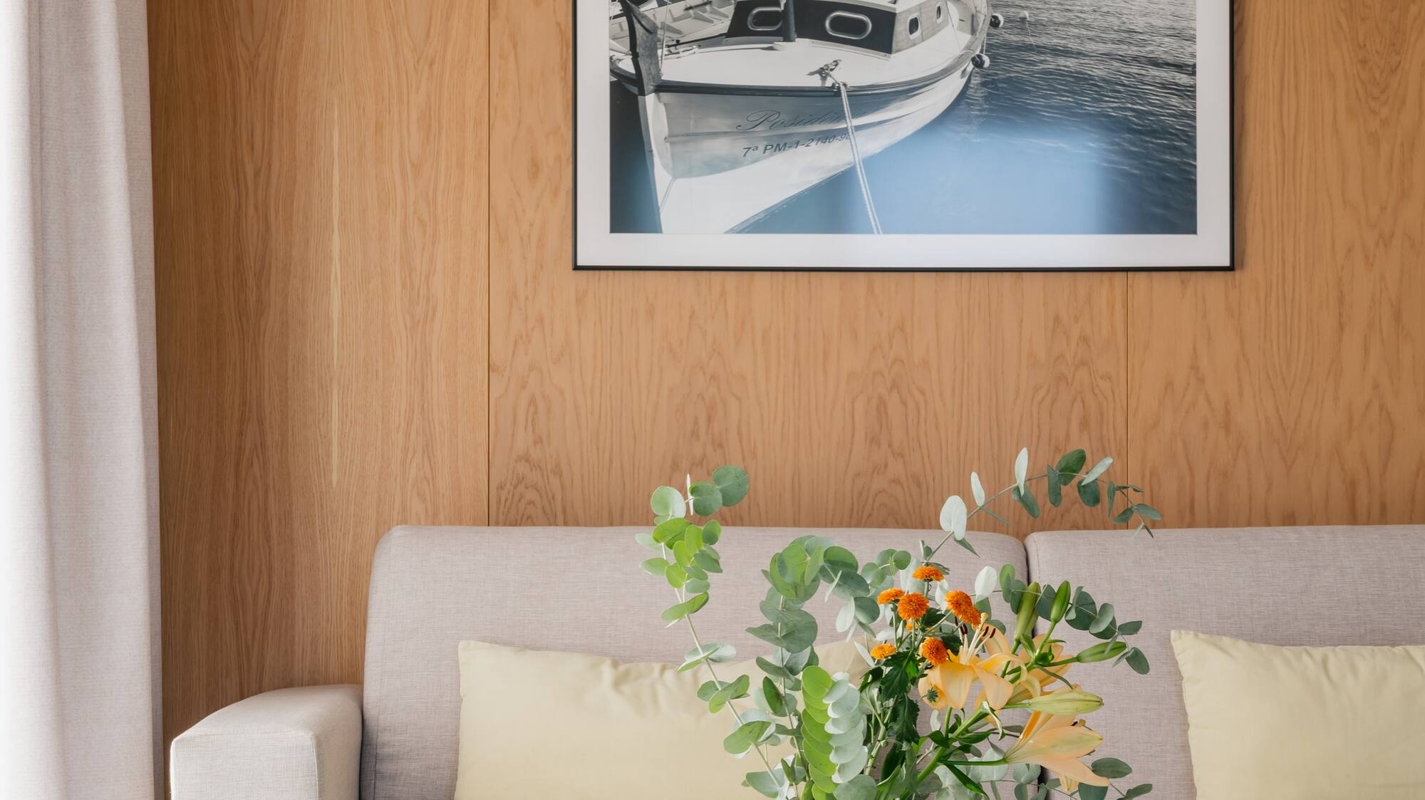 a vase of flowers on a table in front of a picture on a wall