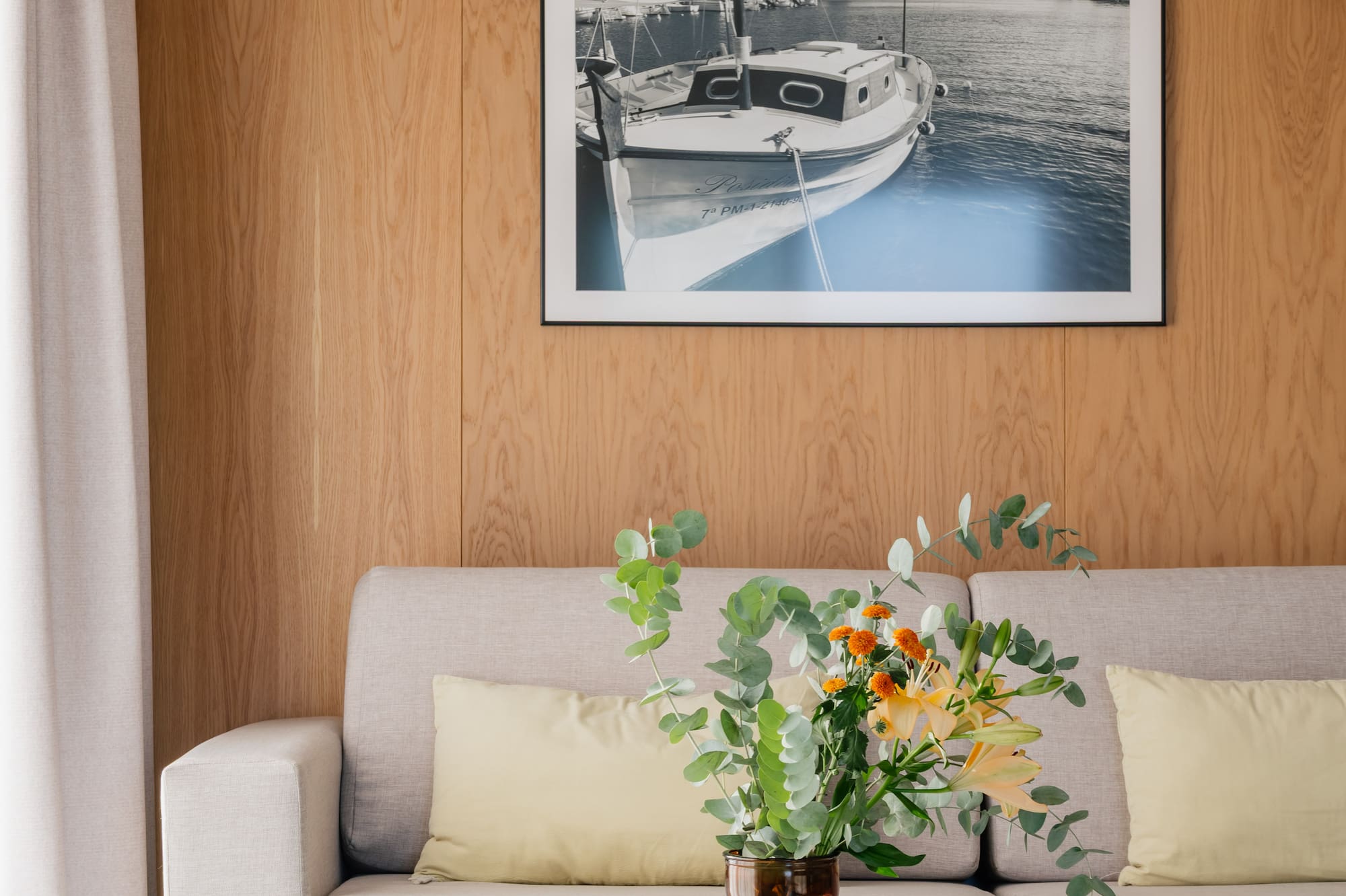 a vase of flowers on a table in front of a picture on a wall