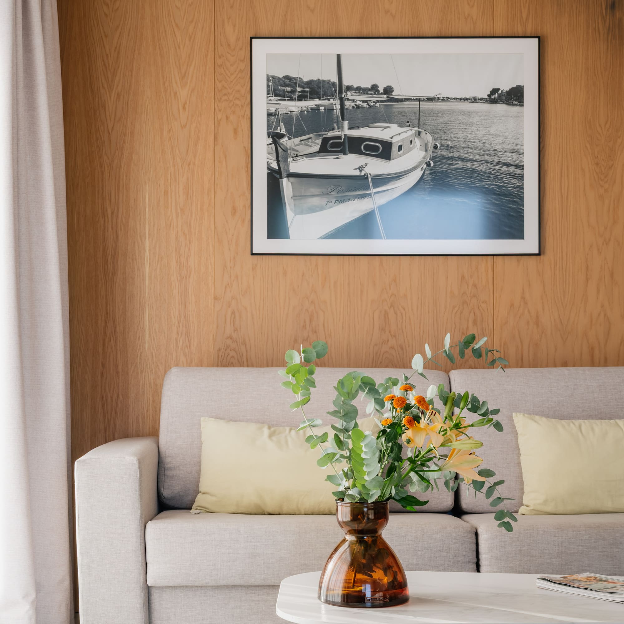 a vase of flowers on a table in front of a picture on a wall