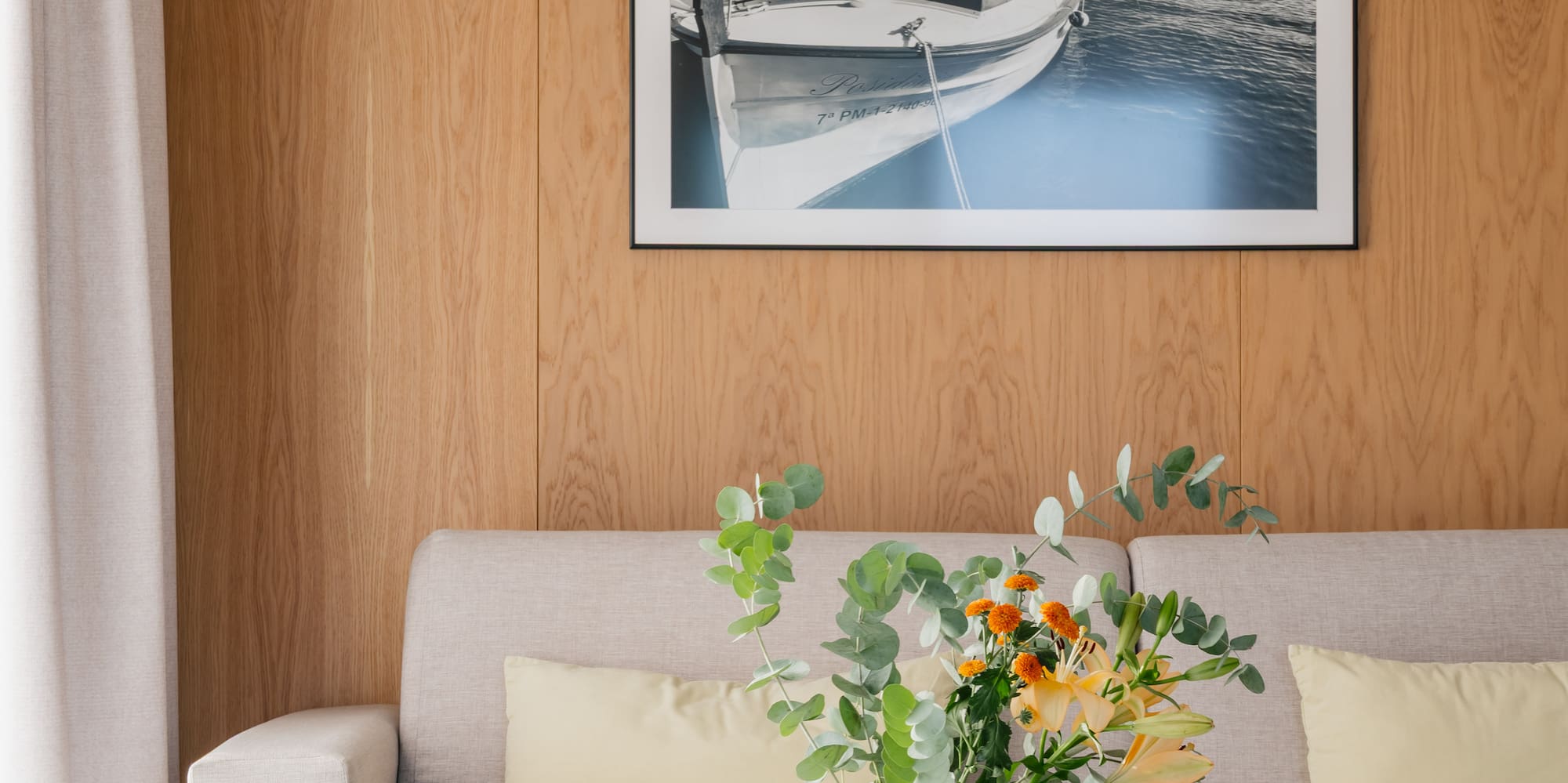a vase of flowers on a table in front of a picture on a wall