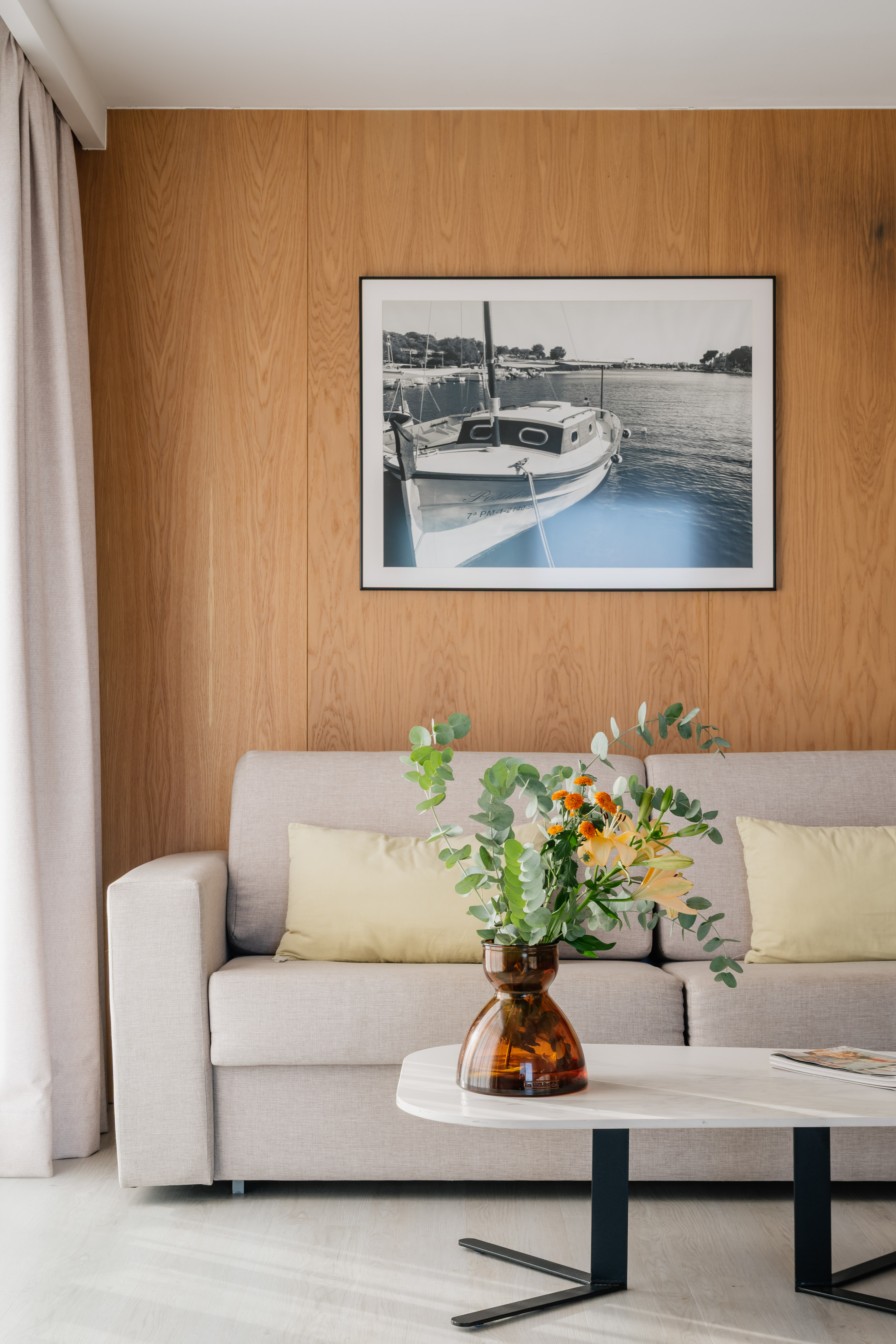a vase of flowers on a table in front of a picture on a wall