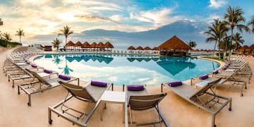 a pool with lounge chairs and straw huts