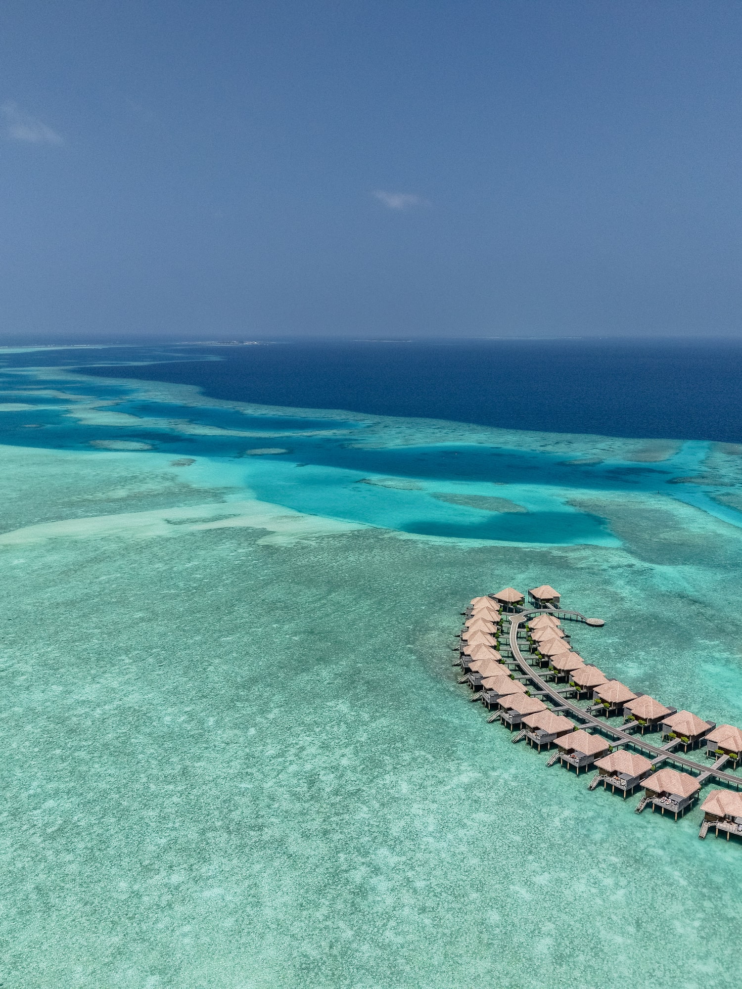 Maldives overwater bungalows over clear turquoise ocean reef.