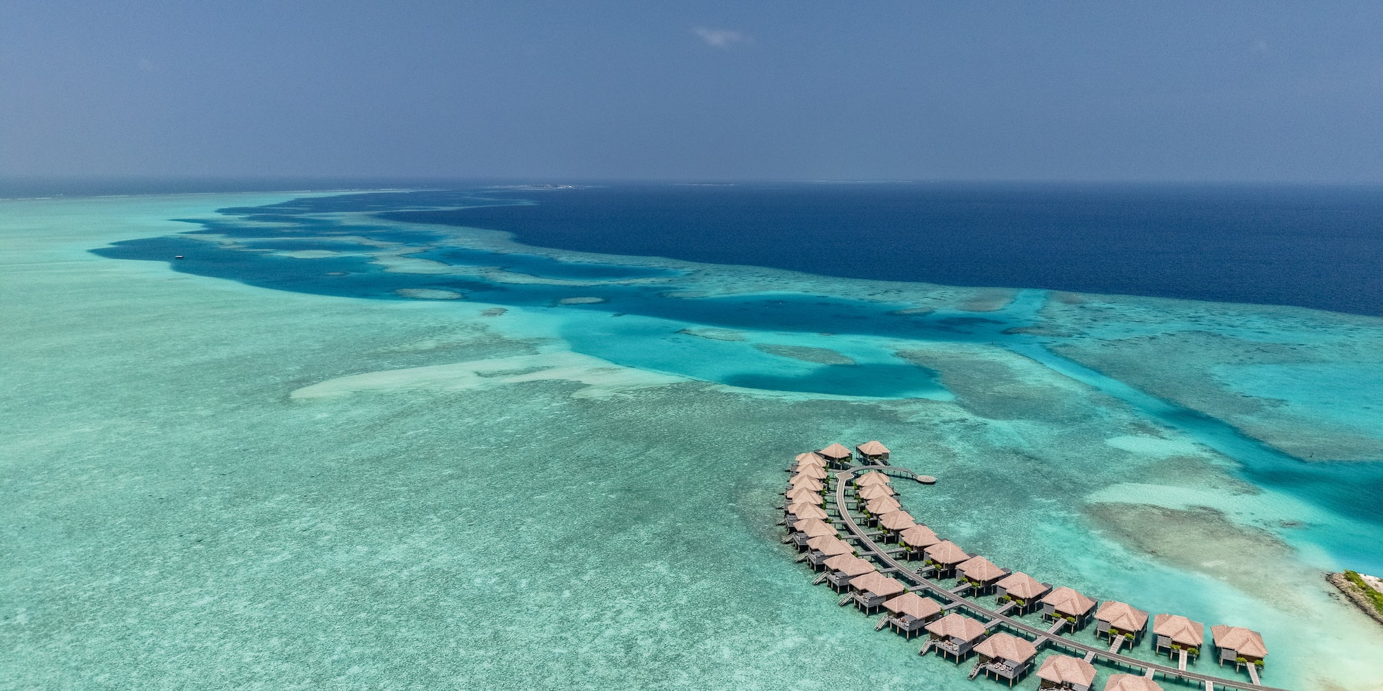 Maldives overwater bungalows over clear turquoise ocean reef.