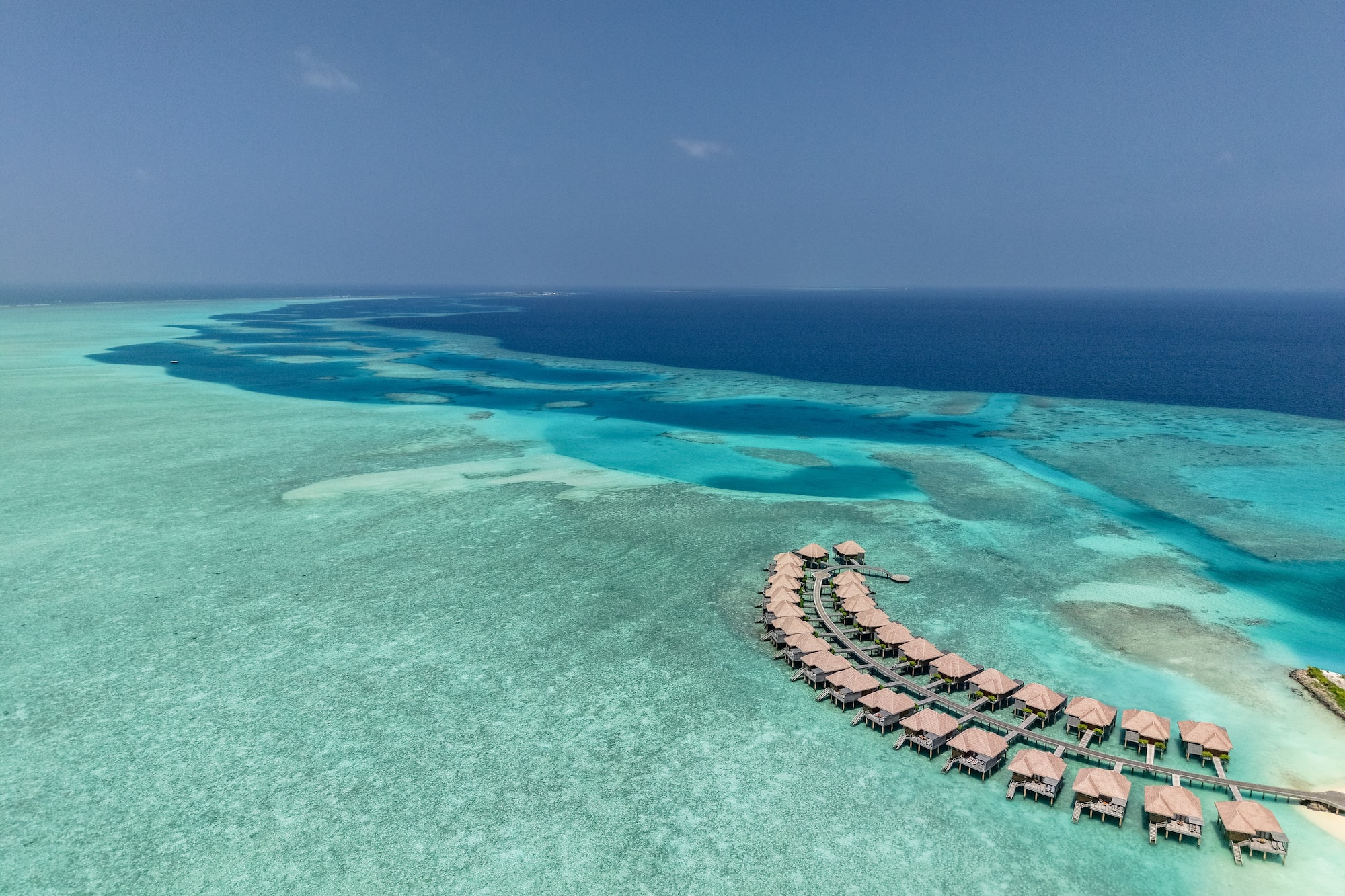 Maldives overwater bungalows over clear turquoise ocean reef.