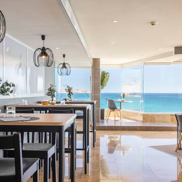 a room with tables and chairs and a view of the ocean