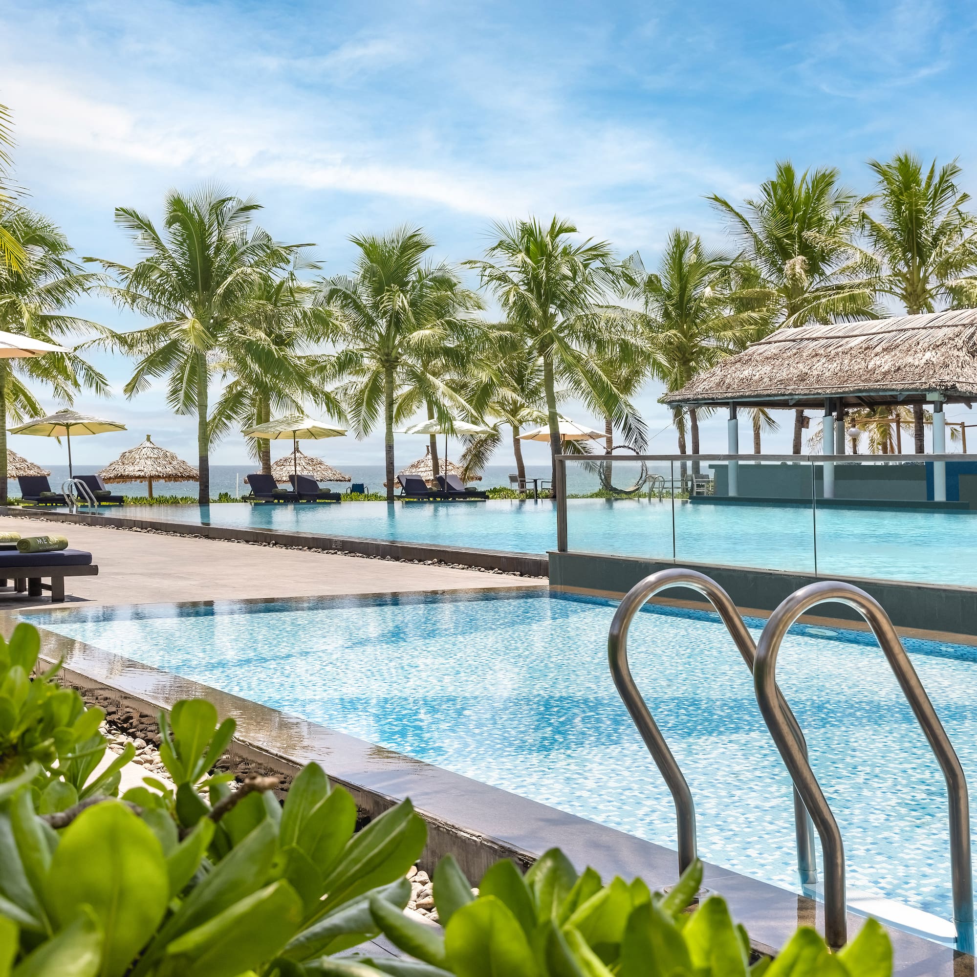 a pool with chairs and umbrellas by a beach