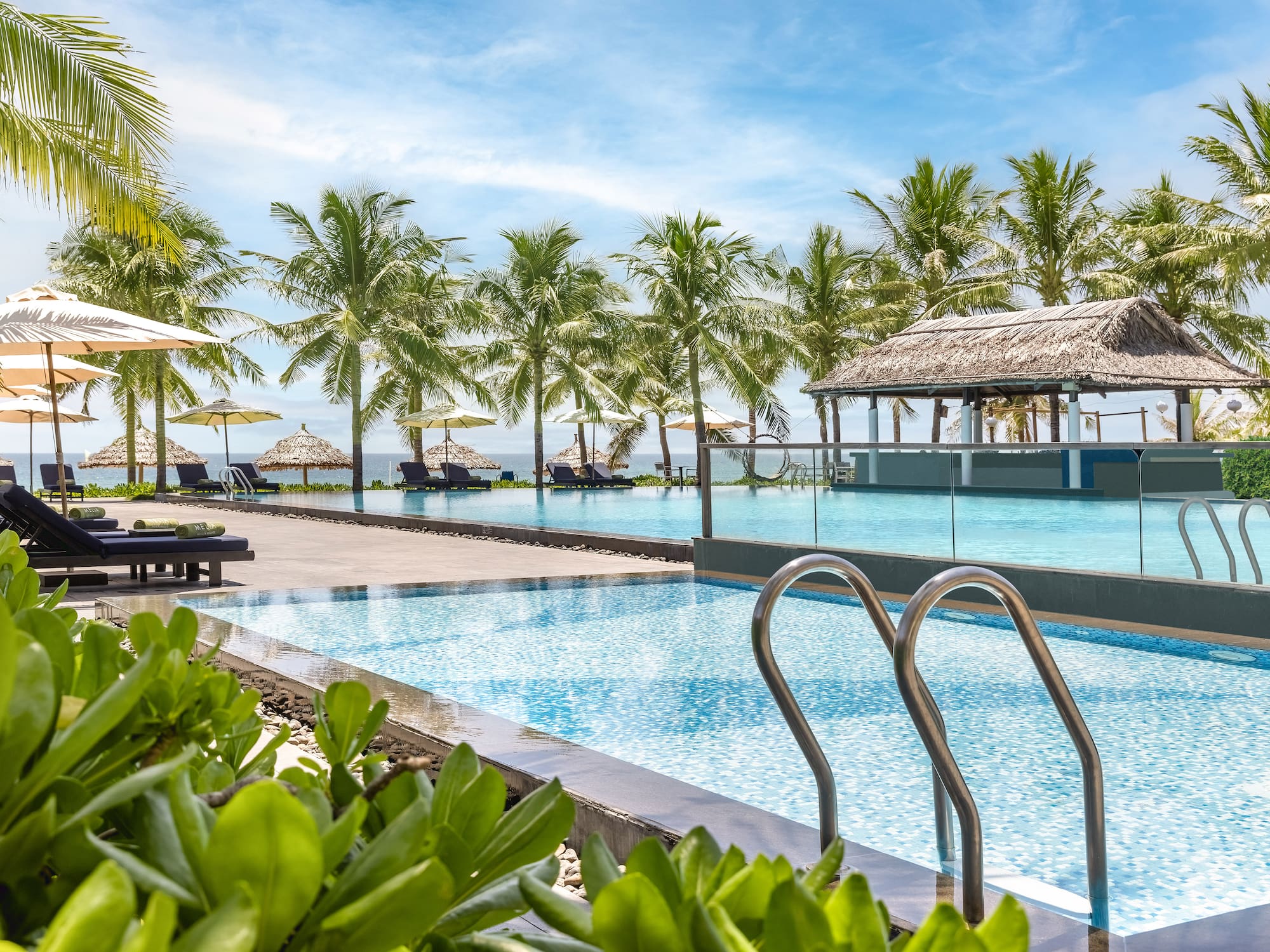 a pool with chairs and umbrellas by a beach