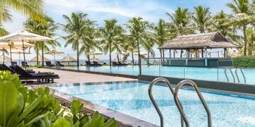 a pool with chairs and umbrellas by a beach