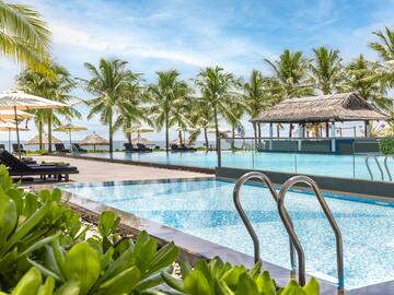 a pool with chairs and umbrellas by a beach