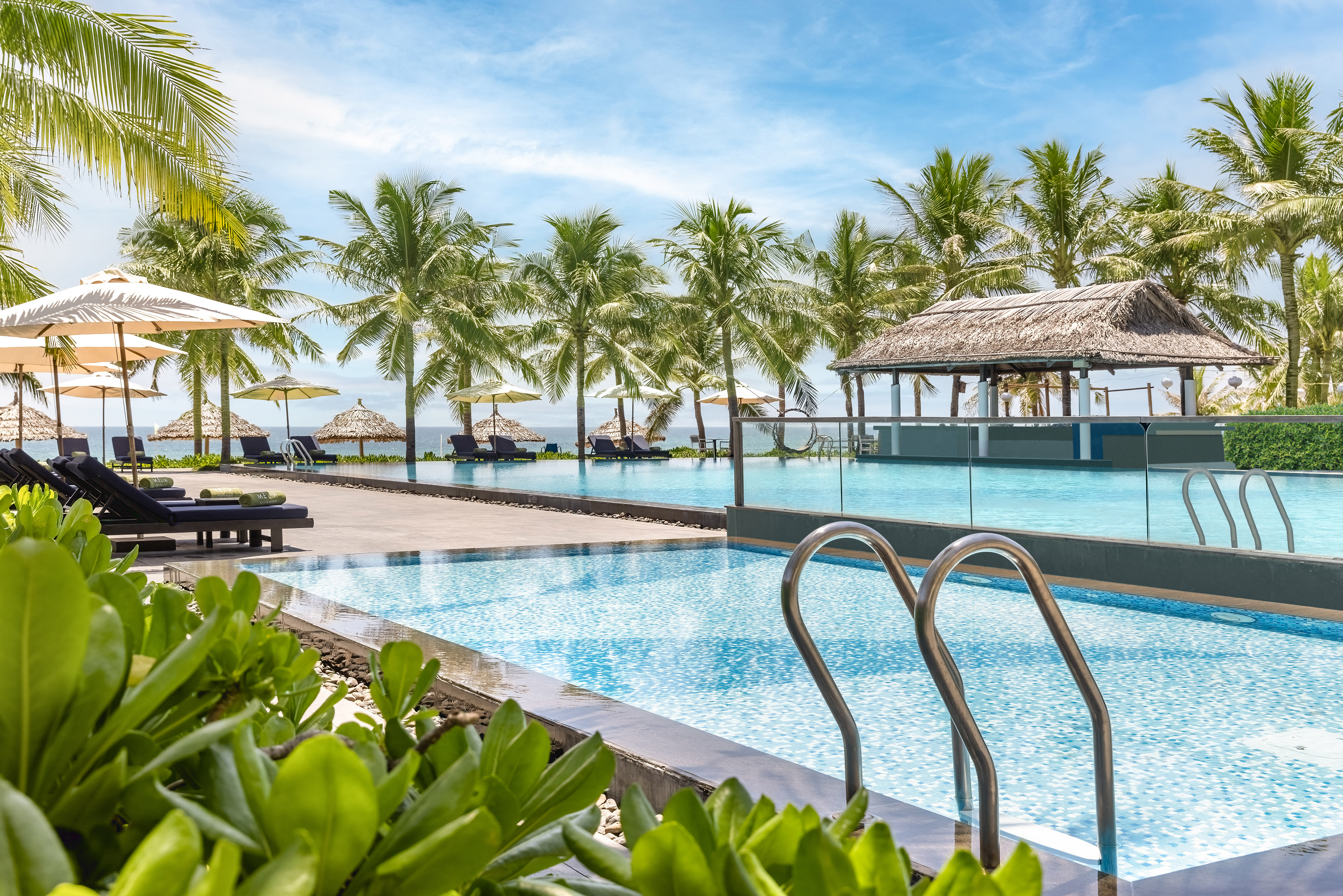 a pool with chairs and umbrellas by a beach