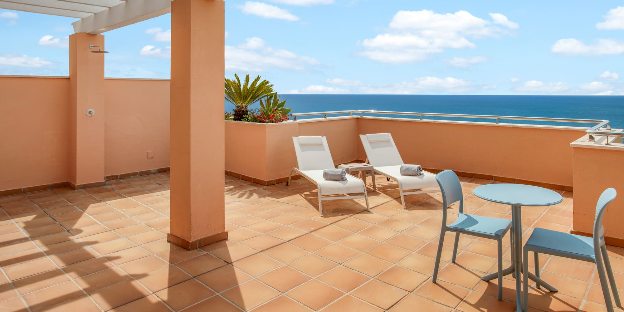 Ocean view terrace with lounge chairs, outdoor dining, and pergola.