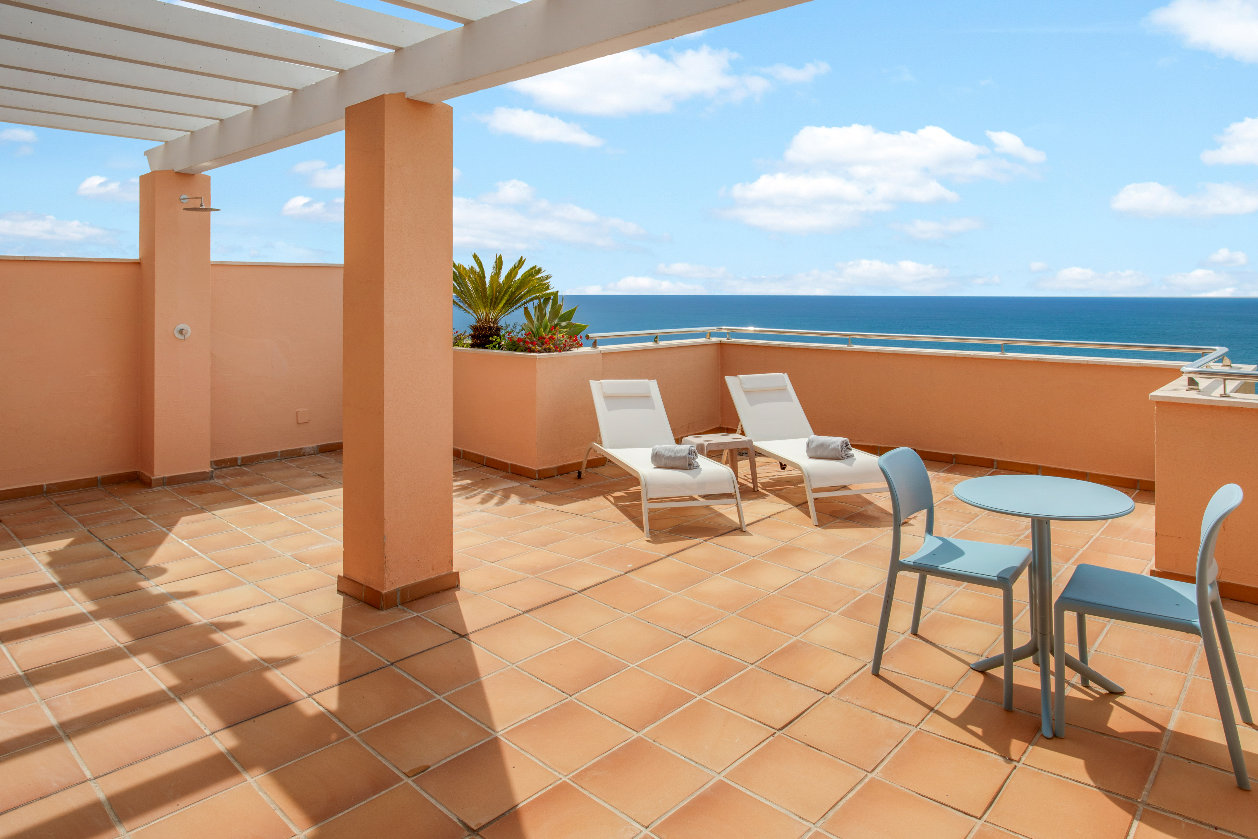 Ocean view terrace with lounge chairs, outdoor dining, and pergola.