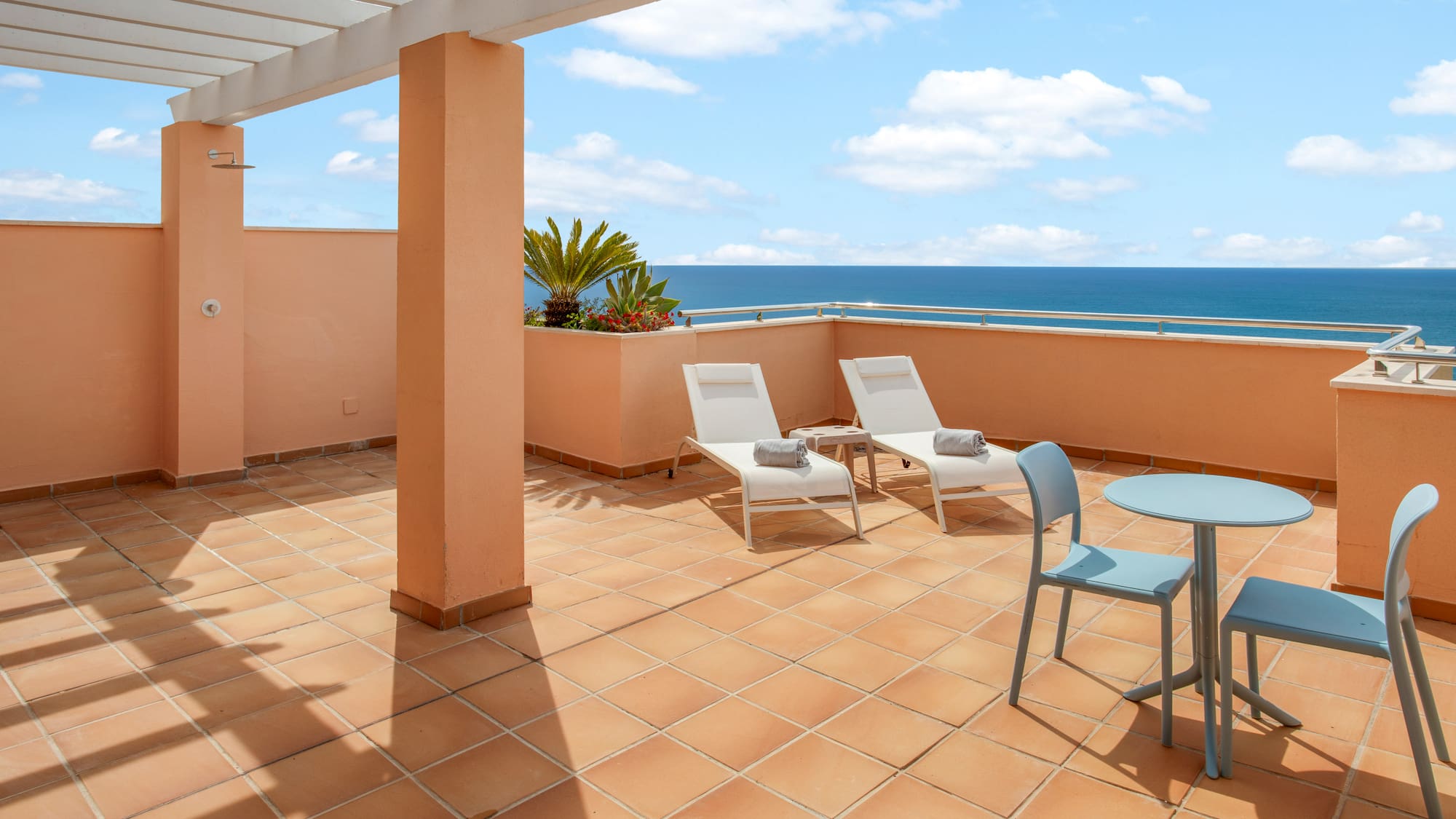 Ocean view terrace with lounge chairs, outdoor dining, and pergola.
