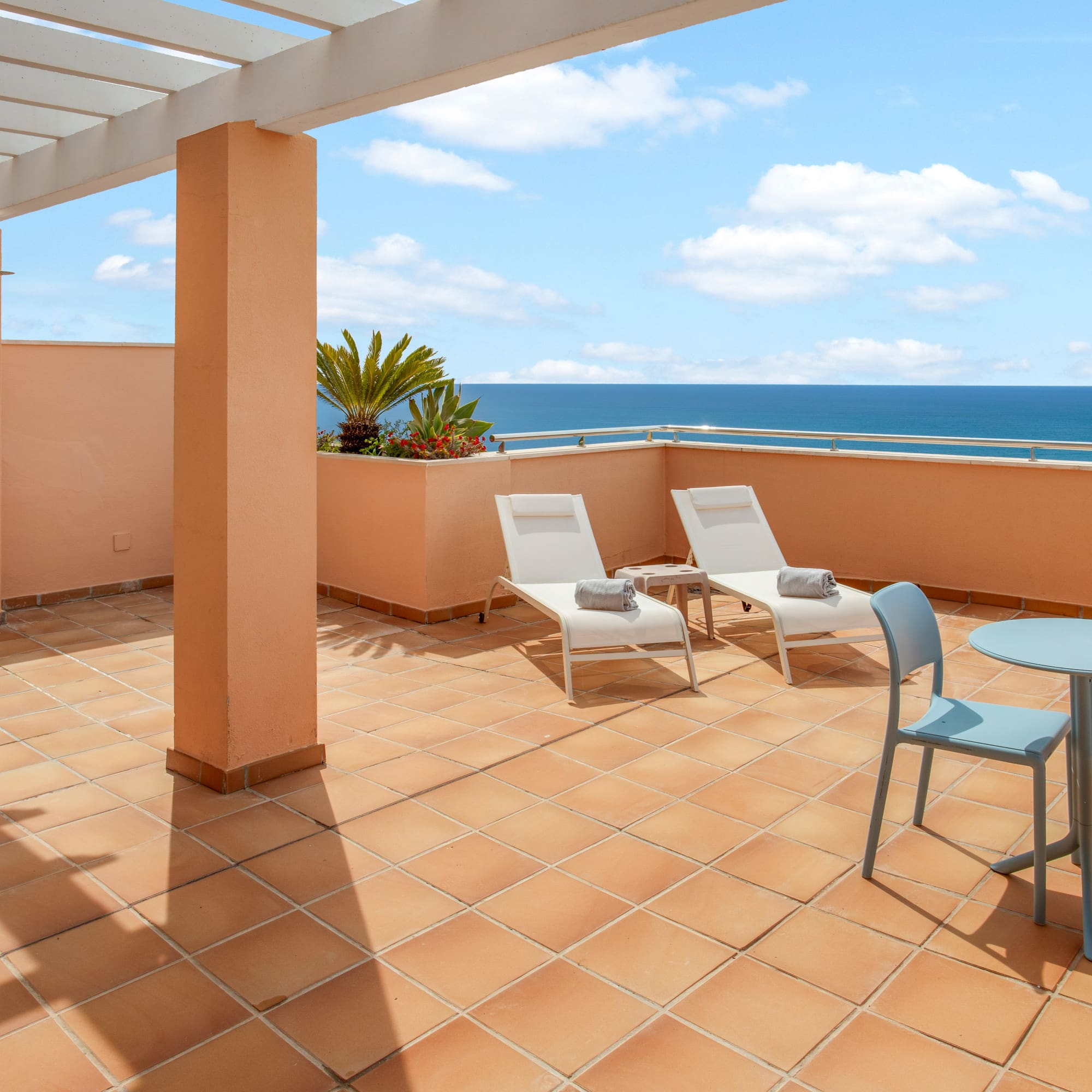Ocean view terrace with lounge chairs, outdoor dining, and pergola.