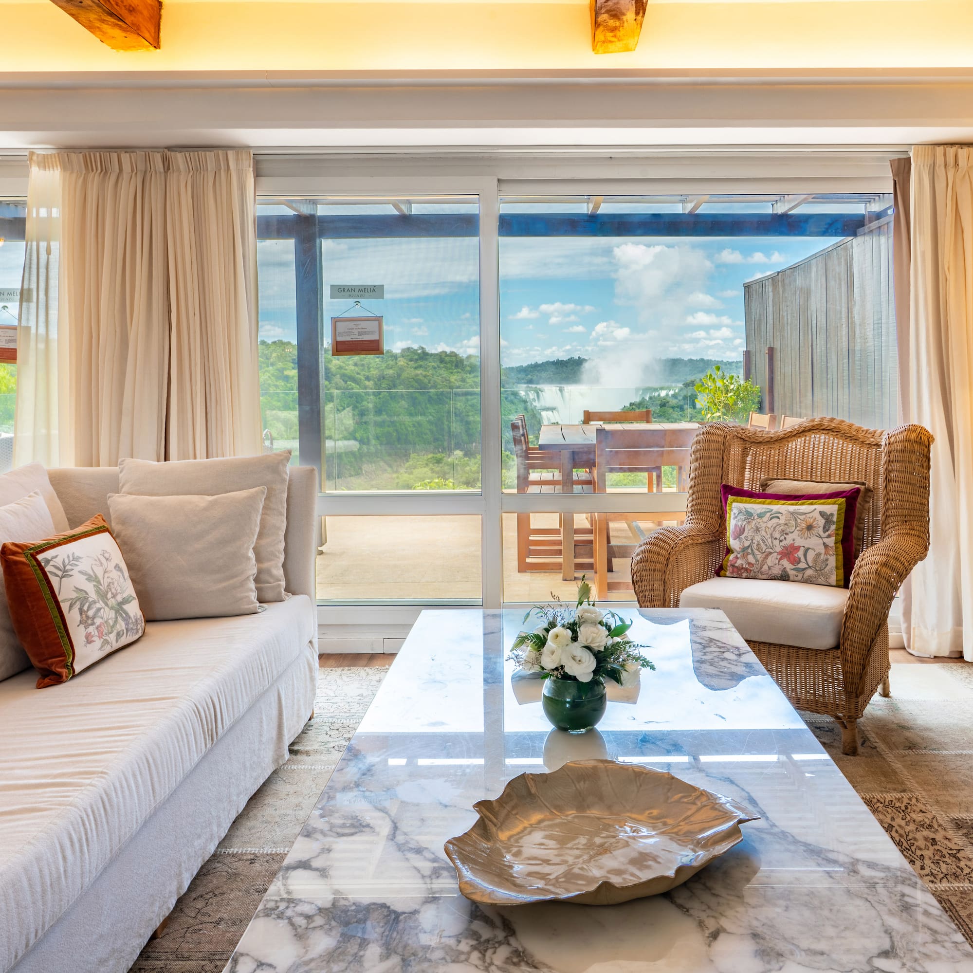 a living room with a marble coffee table and wicker chairs