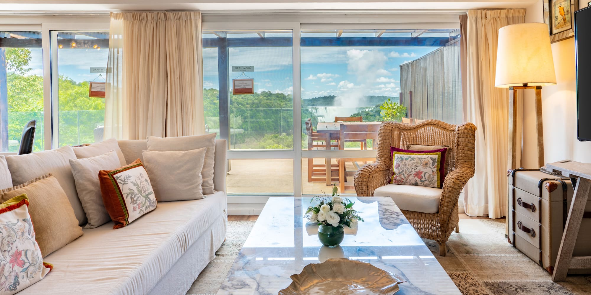 a living room with a marble coffee table and wicker chairs