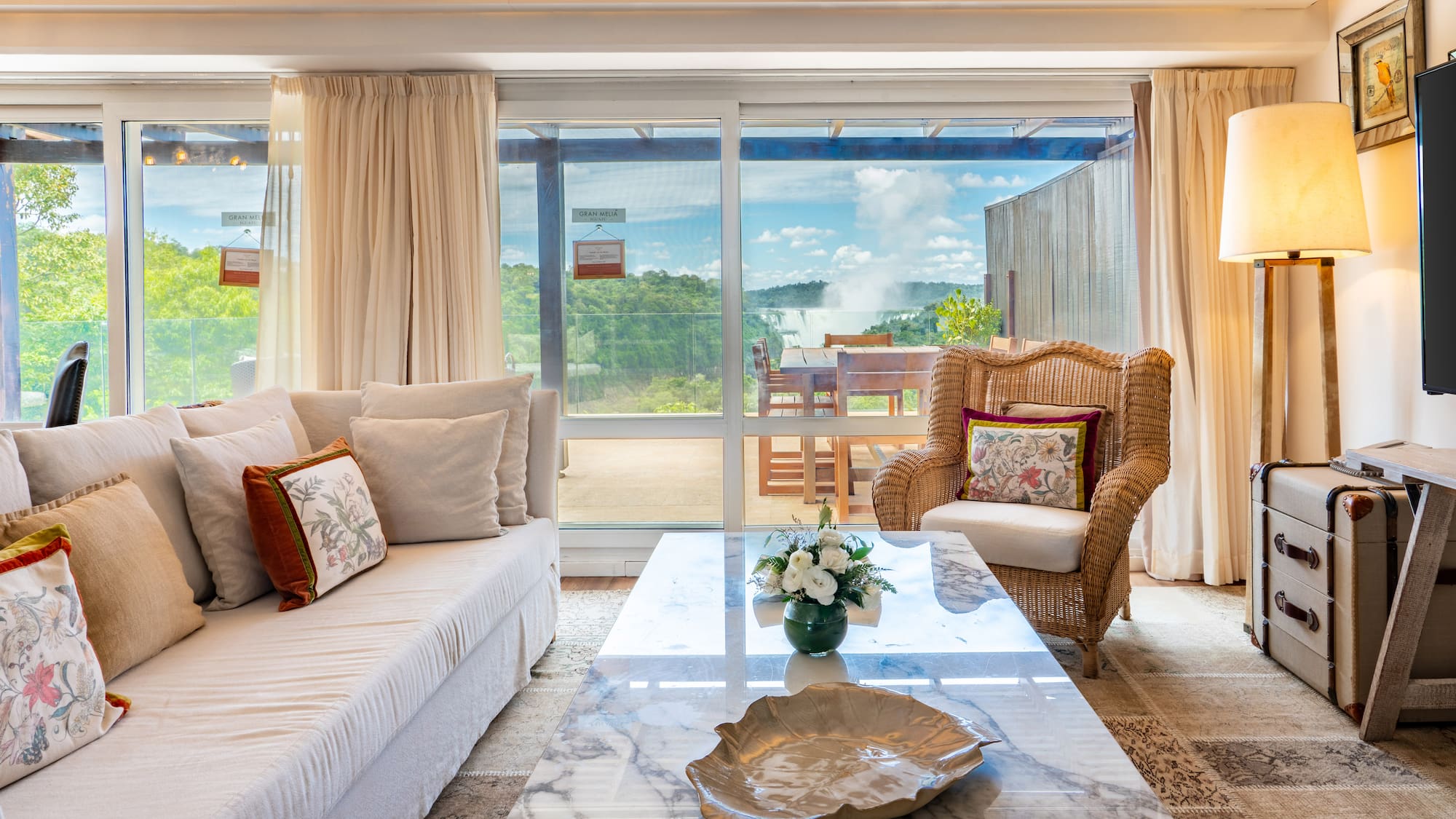 a living room with a marble coffee table and wicker chairs
