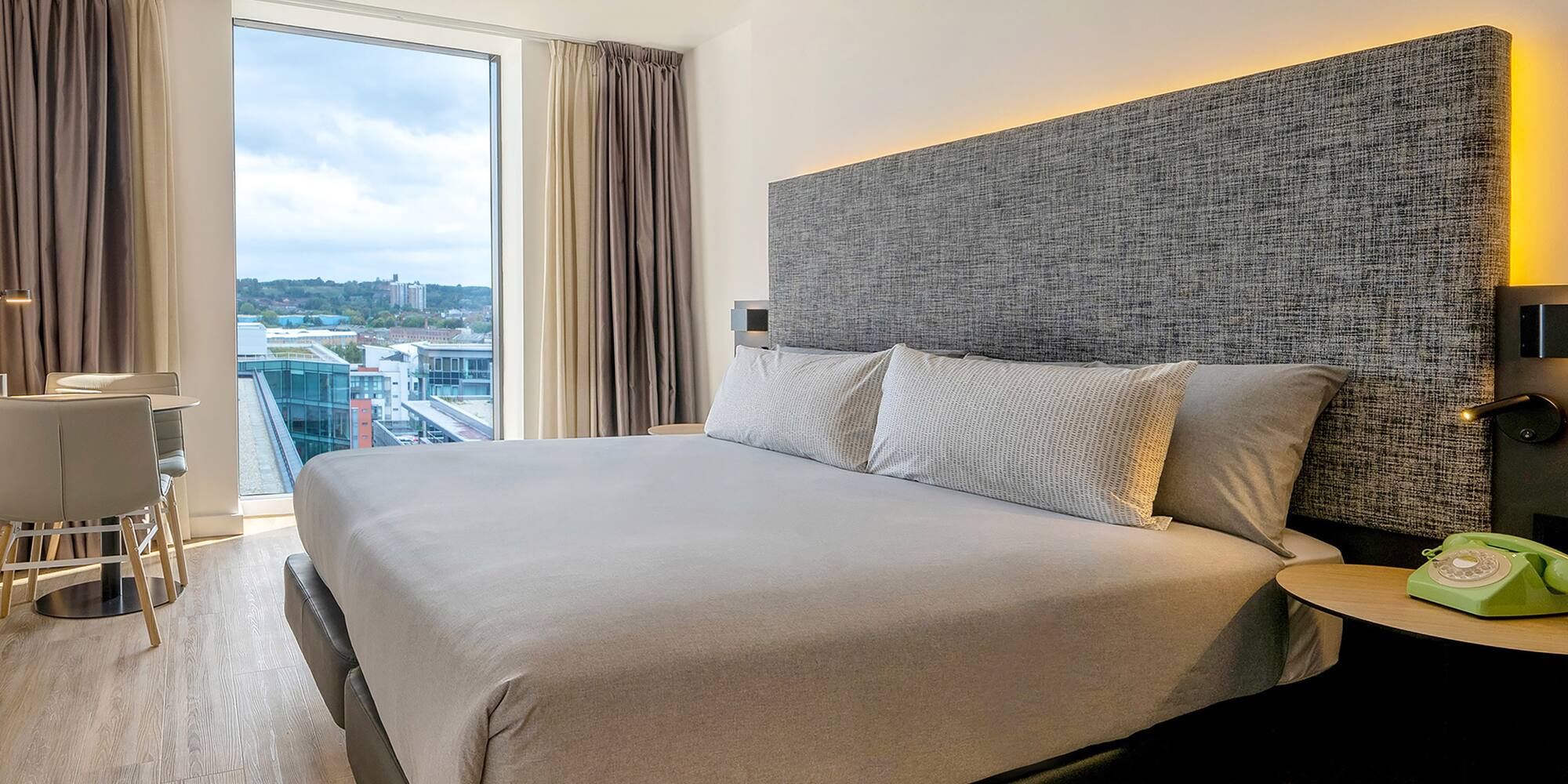 a bed with pillows in a room with a large window