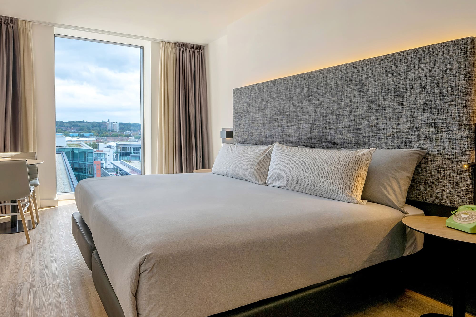 a bed with pillows in a room with a large window