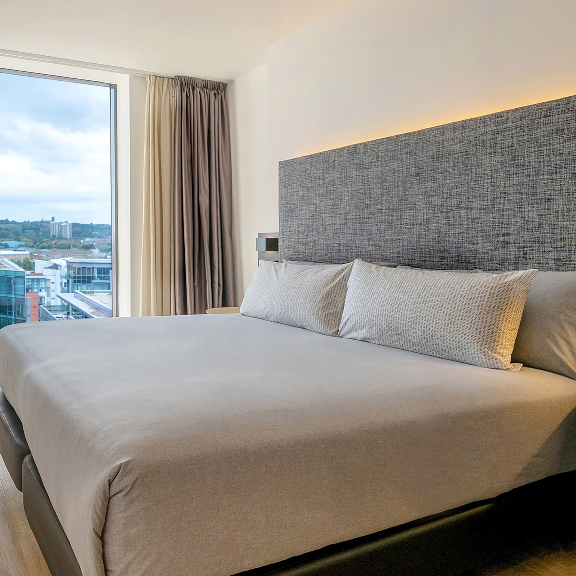 a bed with pillows in a room with a large window