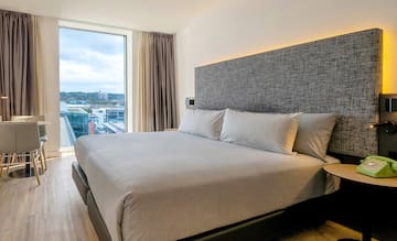 a bed with pillows in a room with a large window