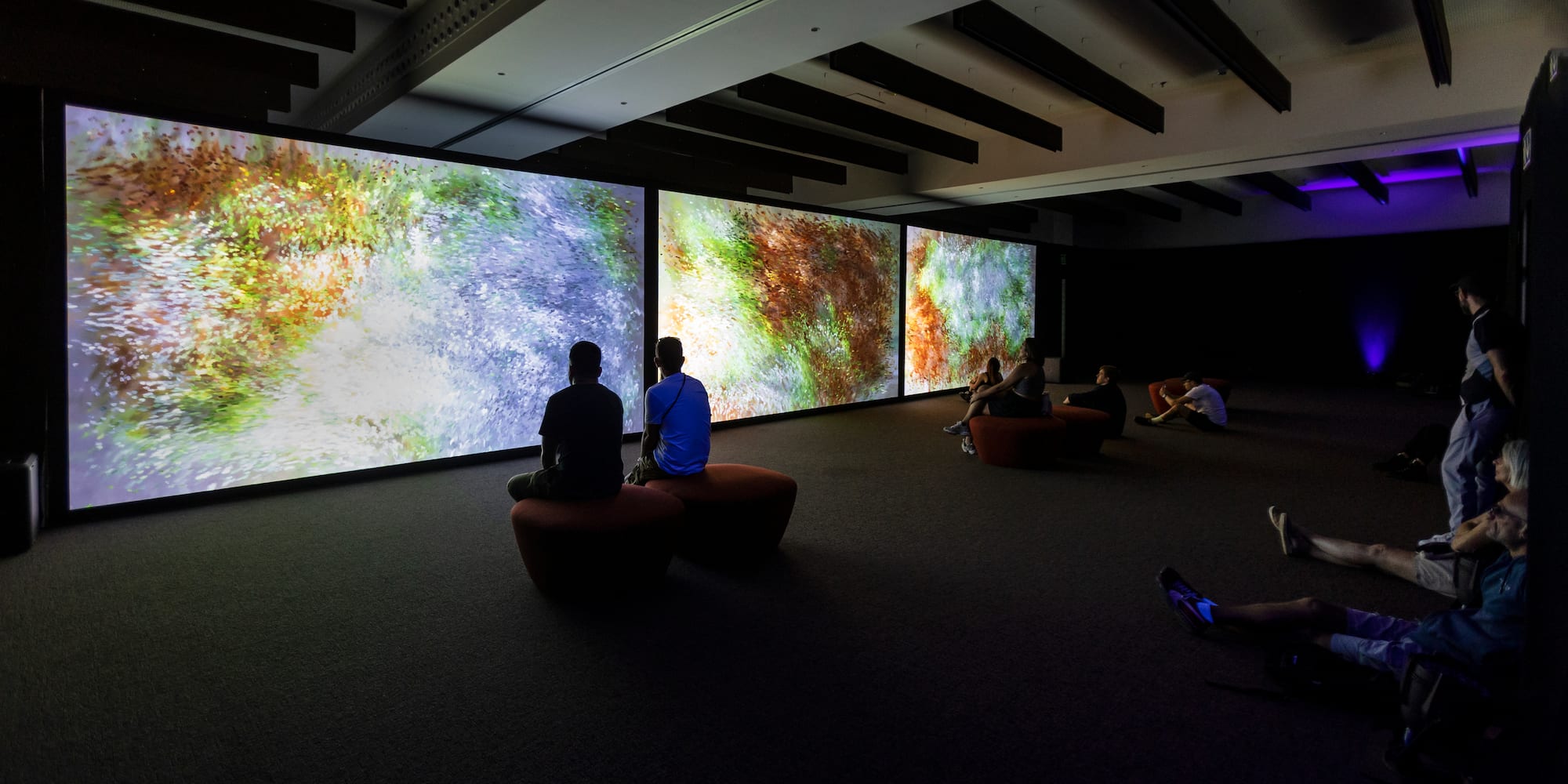 a group of people sitting in a room with large screens