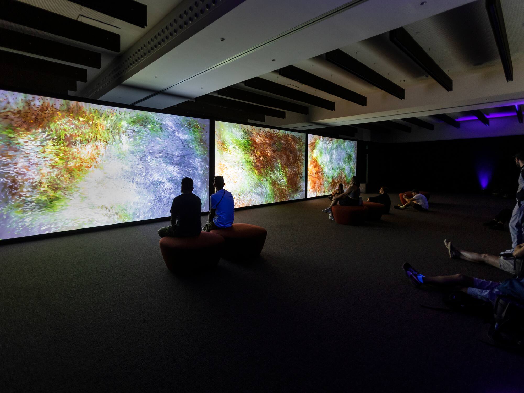 a group of people sitting in a room with large screens