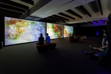 a group of people sitting in a room with large screens